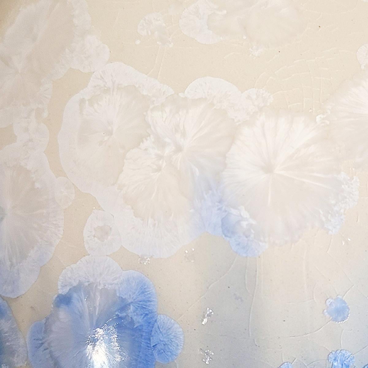 Questo vaso in porcellana smaltata cristallina di Jon Puzzuoli presenta una vibrante tavolozza di colori blu e crema. Gli smalti cristallini sono speciali smalti ceramici in cui i cristalli di silicato di zinco crescono all'interno dello smalto