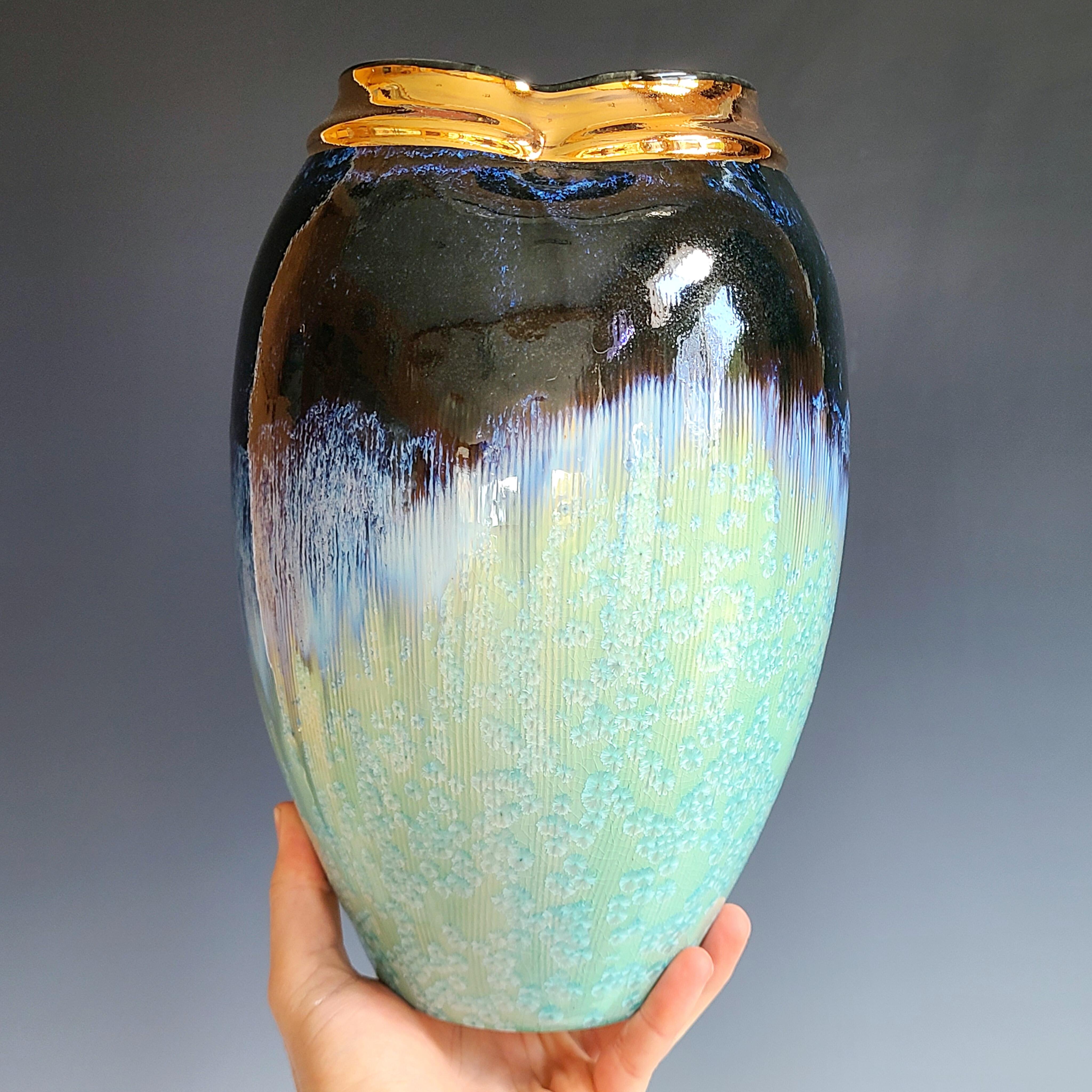 This glazed porcelain vessel by Jon Puzzuoli features a deep, midnight blue and mint green palette, with a crystalline glaze and 18K gold luster along the neck. The artist's stamp is located at the base of the vessel.

Crystalline glazes are special