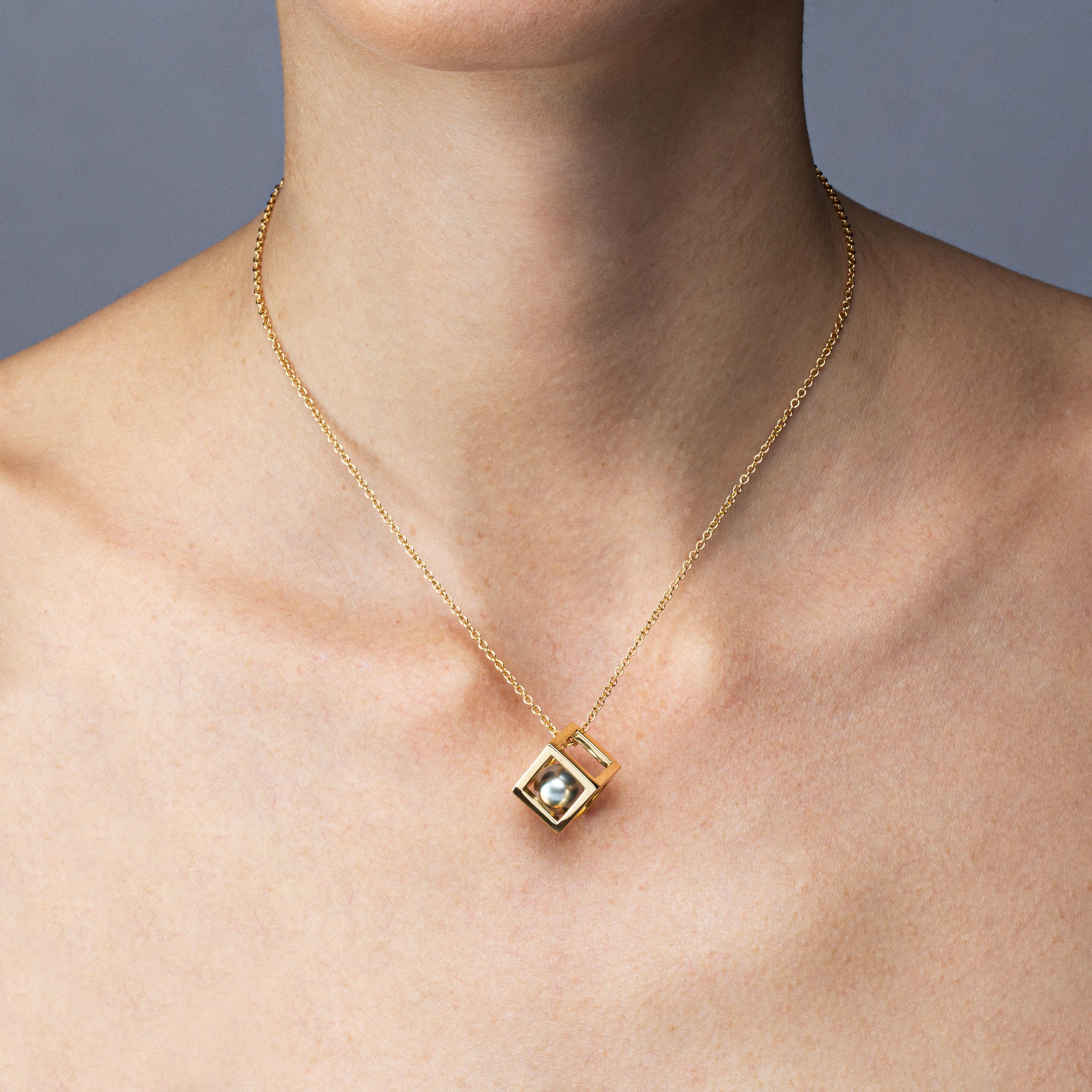 Alex Jona design collection, hand crafted in Italy, 18 Karat yellow gold cube pendant measuring 13.40mmx13.40mm, enclosing a 12mm Tahiti grey pearl weighing 25 carats, suspending from a 39cm long chain necklace.

Alex Jona jewels stand out, not only