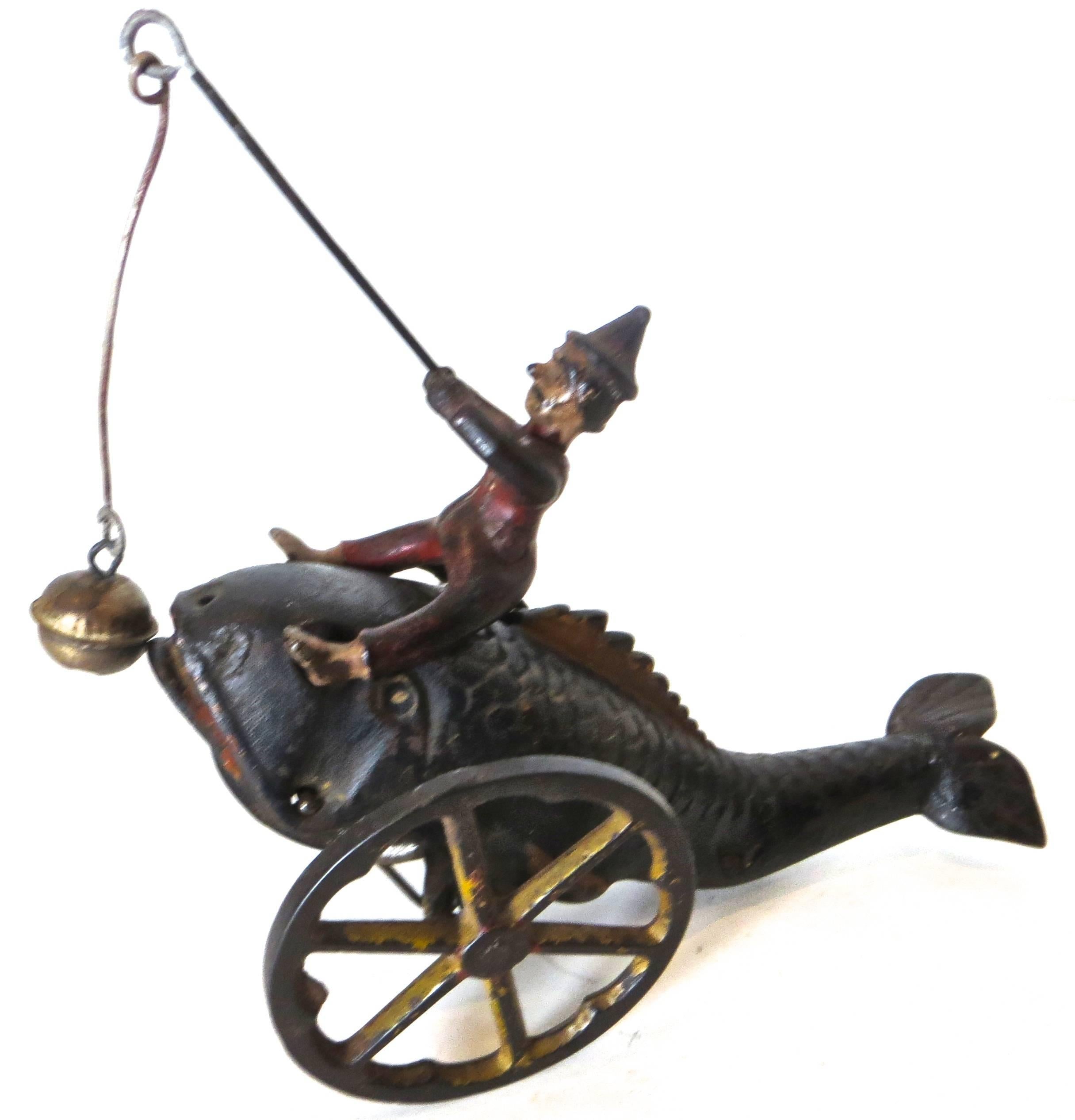 This hand-painted cast iron floor toy was pushed or pulled along the floor with a string tied to the front of the whale. Jonah moves up and down and back and forth, and in so doing he moves the bell so as to tease the whale who opens and closes his