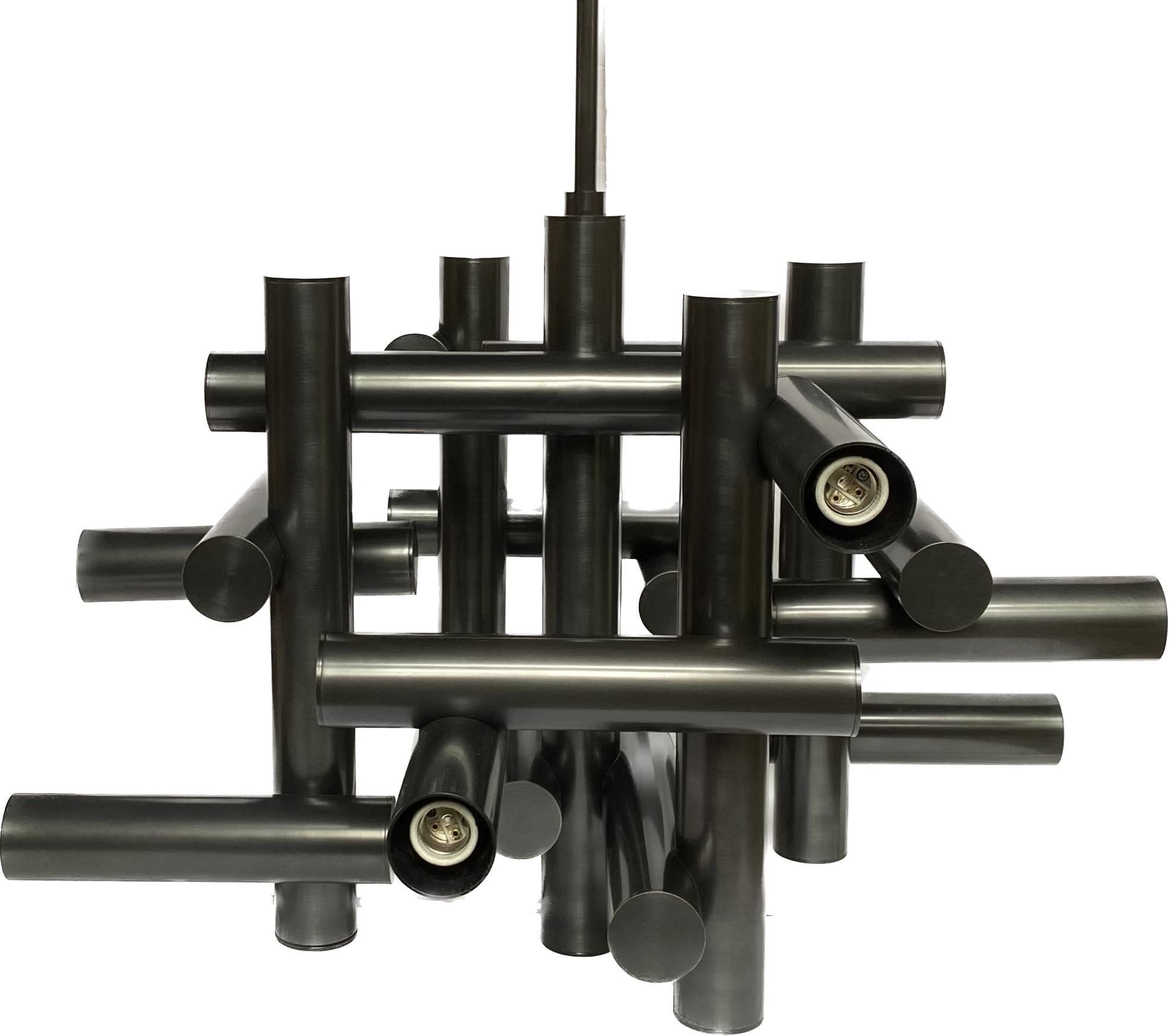 Modern tubular Milano chandelier by Jonathan Alder, for Robert Abbey. This sculptural tiered statement chandelier features a deep bronze tone metal. This was a floor model in our showroom and is being offered at a special price. It is brand new and