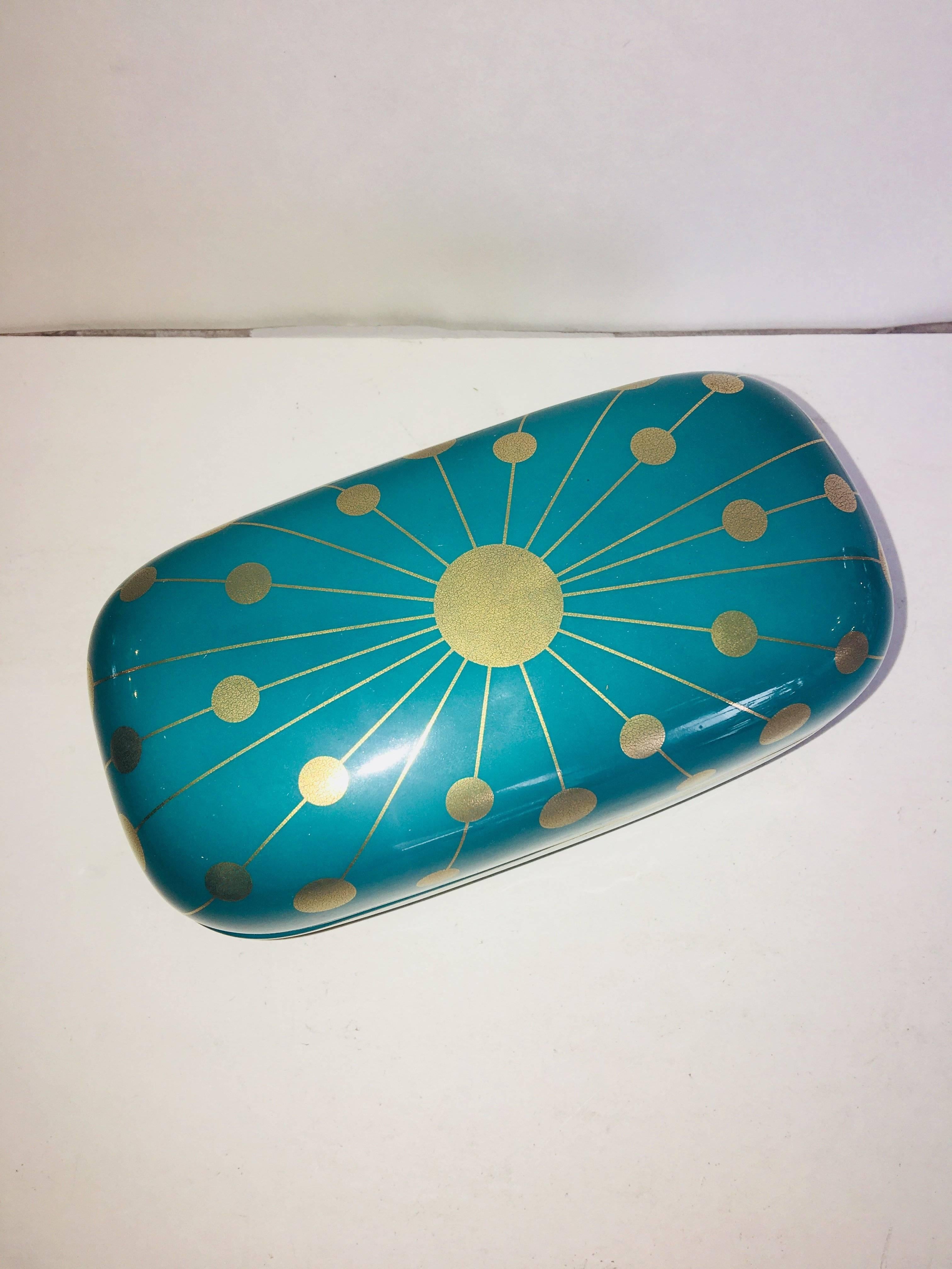 Jonathan Adler's signature approach to design is instantly recognizable, combining vintage influences with a modern freshness. This porcelain box offers chic storage for small trinkets. The pure gold design stands out against the rich turquoise
