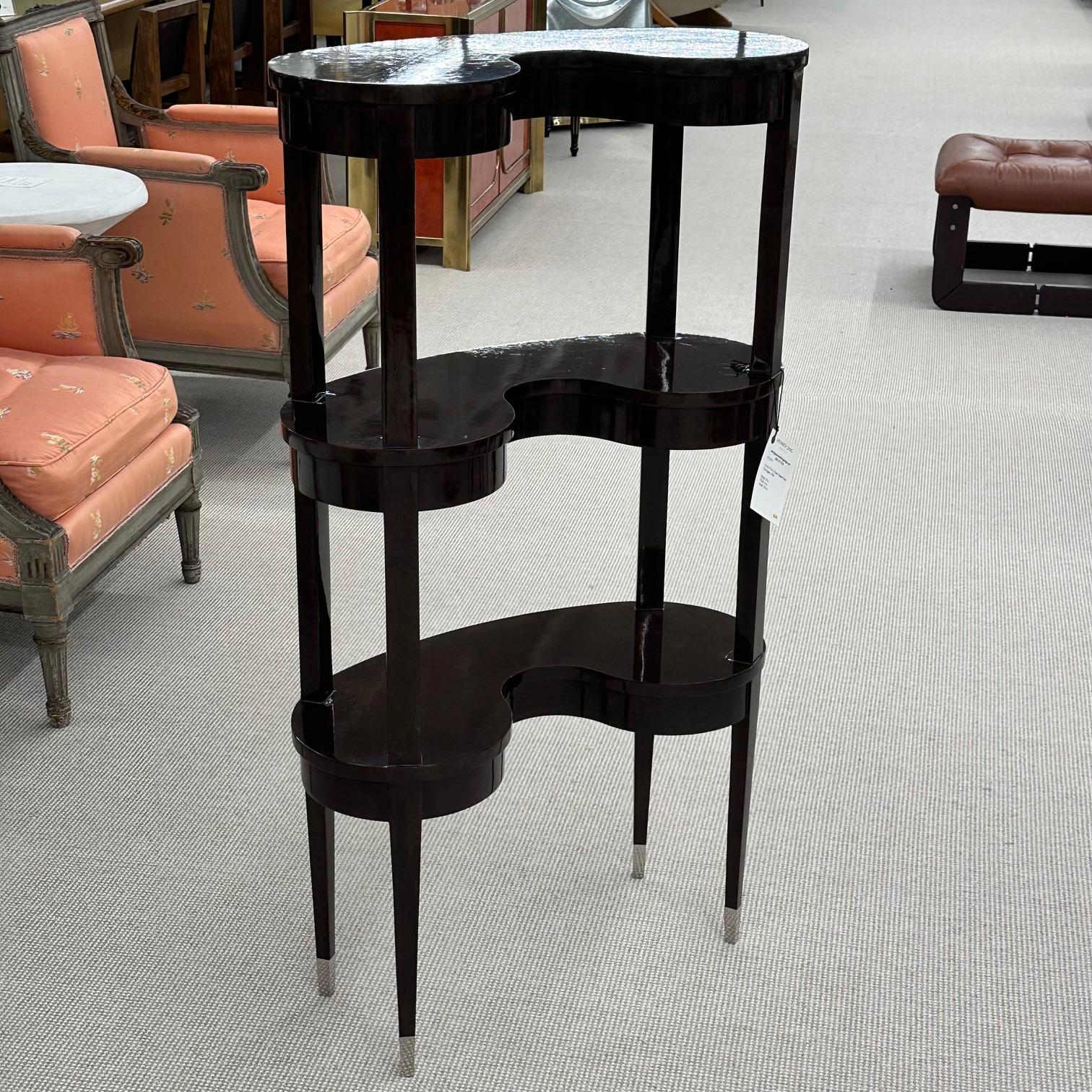 Jonathan Charles kidney shaped three-tier etagere. Having a black eucalyptus case and stainless steel caps to the feet. Wonderfully decorative Hollywood Regency style shelving unit or etagere.