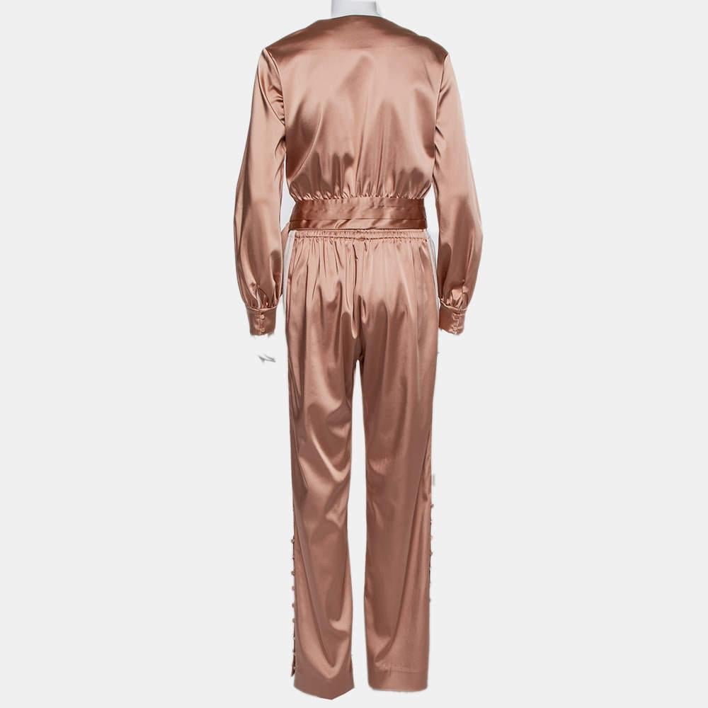 A pretty set by Jonathan Simkhai consisting of a top and track pants. The salmon pink top comes with long sleeves and front wrap detail. The matching pants come in a wide-leg silhouette and contrast trim on the sides. You can wear the top and skirt