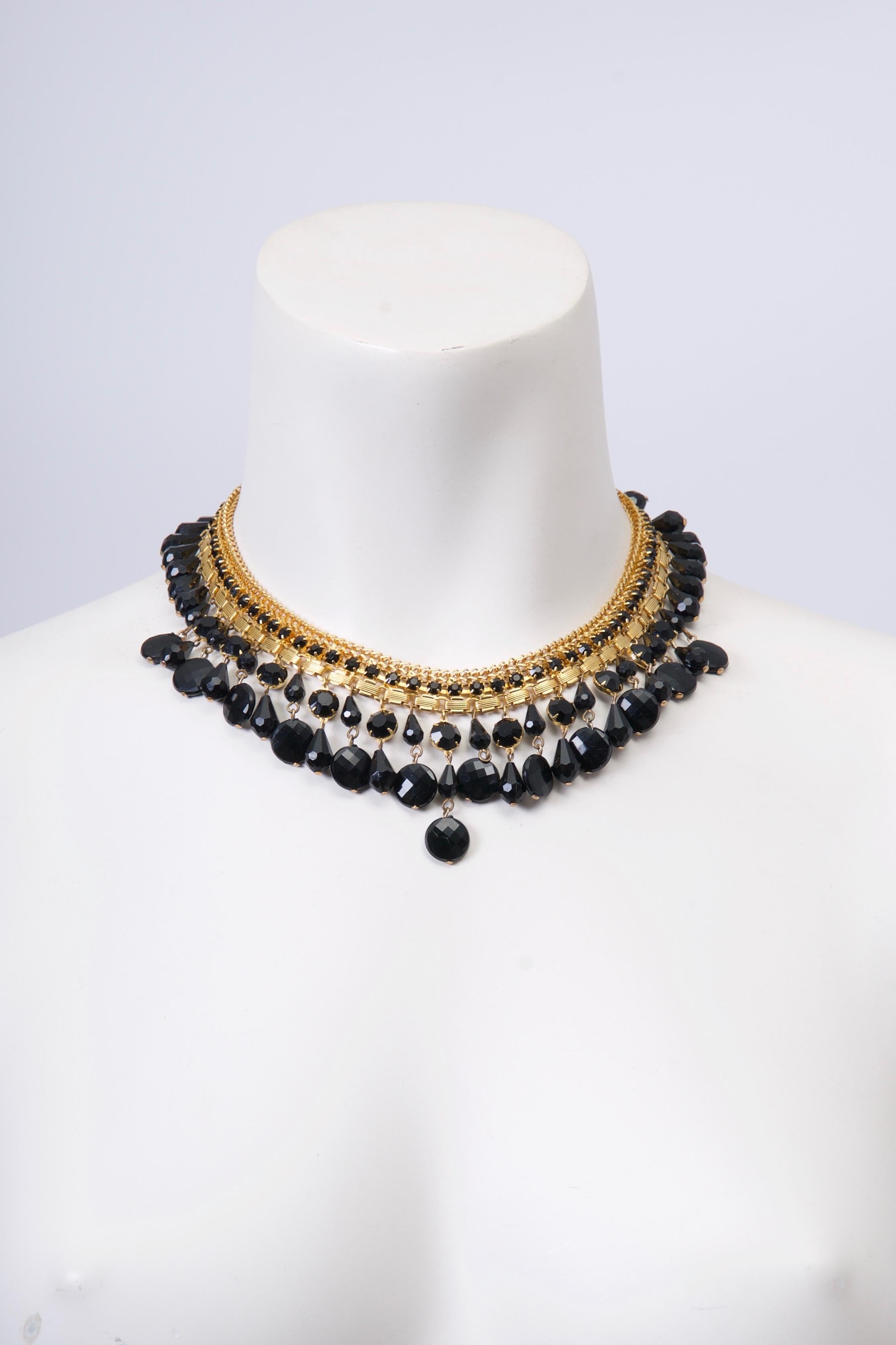 Goldtone and black bead necklace by Jonné, a short-lived division of Schrager, sits gracefully at the nape of the neck. A double row of various faceted black beads are suspended from the goldtone neckpiece, which is composed of three different rows,