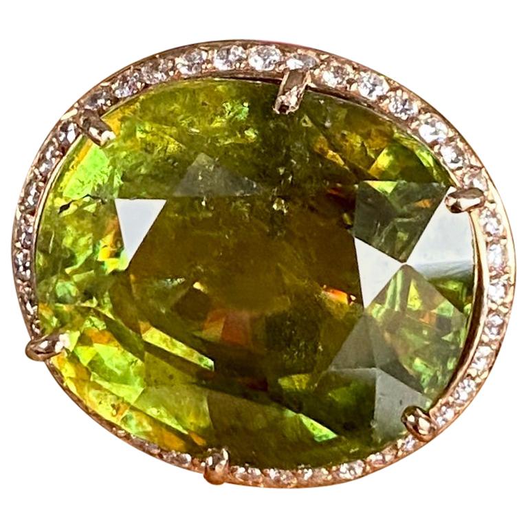 A sphene solitaire cocktail ring of 18.92 carats surrounded by diamond pave, handcrafted in 18 karat rose gold.

This exquisite one-of-a-kind large sphene ring of 18.92 carats is a true beauty with its gorgeous lime green hues, brilliant fire, and