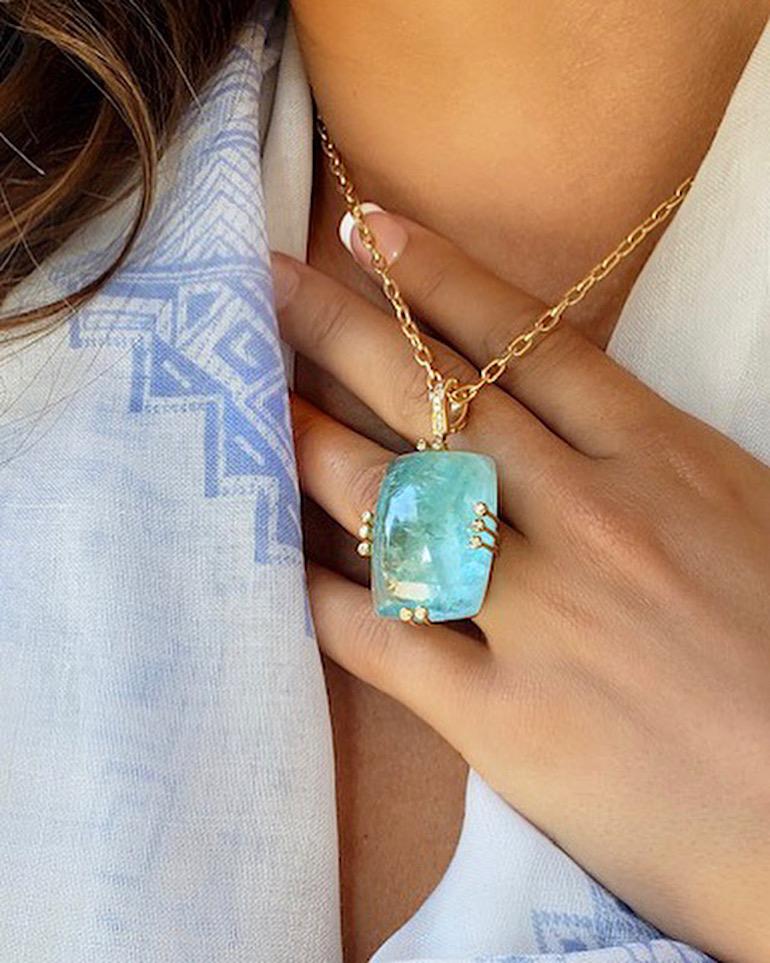 A cabochon aquamarine and diamond pendant necklace, handcrafted in 18 karat yellow gold.

A beautiful one-of-a-kind aquamarine and diamond pendant, equally pretty hanging from a gold chain or a silk cord. The color of this translucent aquamarine is