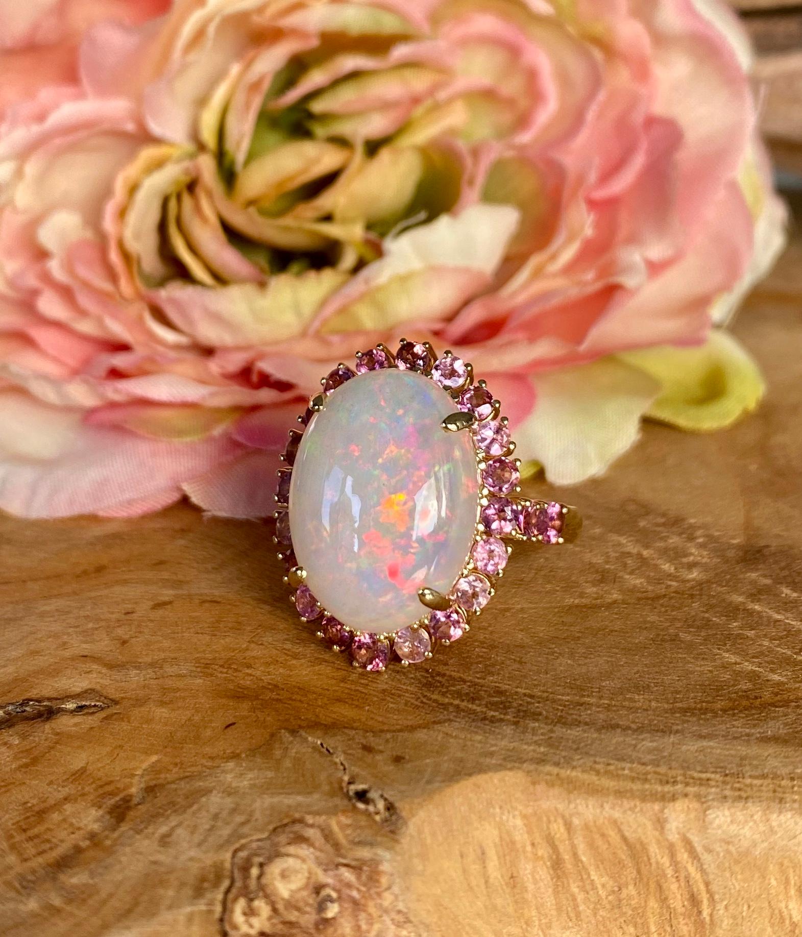Joon Han one-of-a-kind cocktail ring of an oval Ethiopian opal surrounded by multi-pink tourmalines, handcrafted in 18 karat yellow gold. US size 6.

This stunning rainbow-hued opal ring comes to life when worn, encircled by rich multi-hued pink
