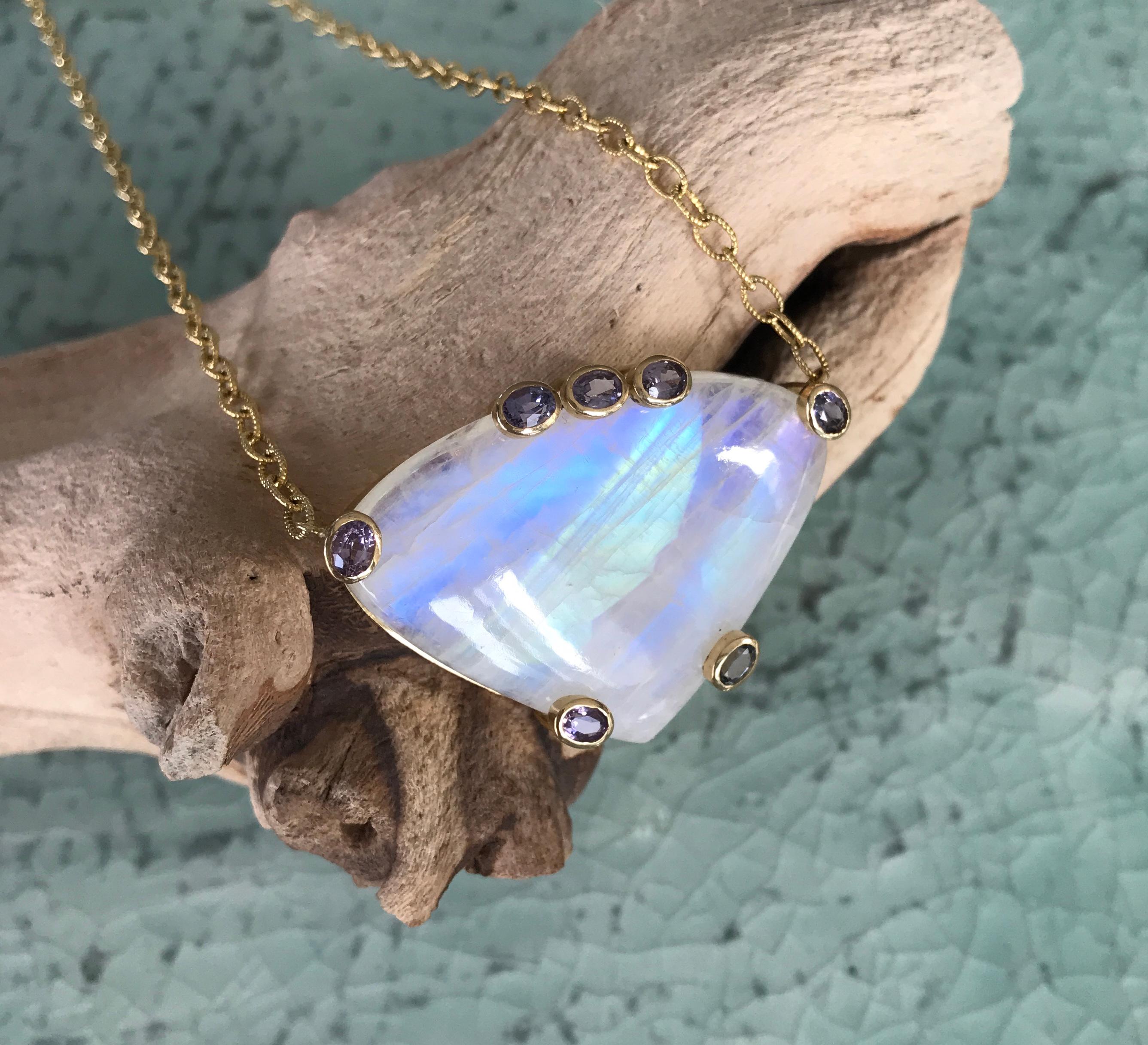 Fancy cut cabochon rainbow moonstone pendant, almost 2 inches across, with purple spinels, handcrafted in 18 karat yellow gold, and hanging on a 14 karat gold chain necklace. Total necklace length is 18 inches.

This one-of-a-kind rainbow moonstone