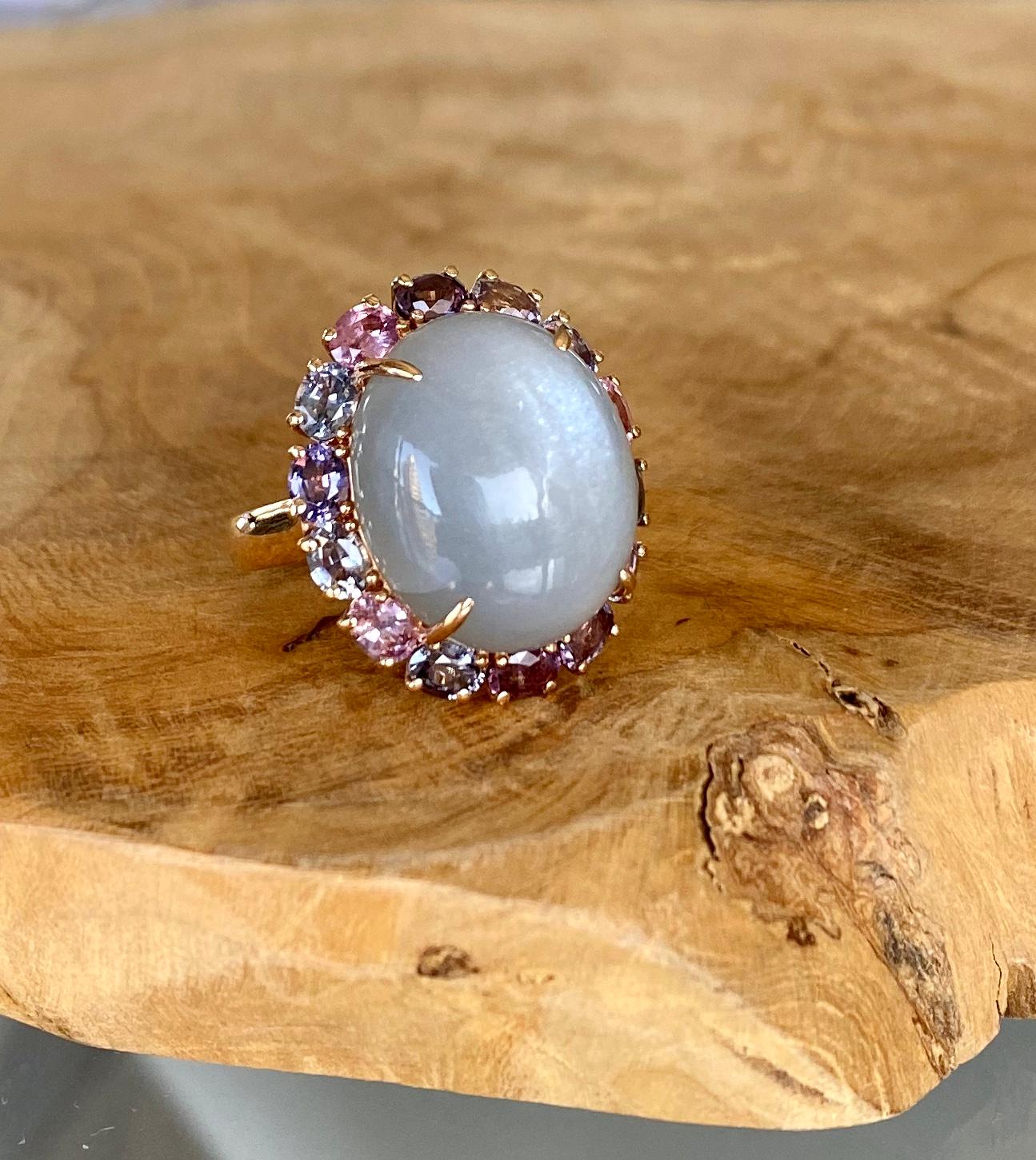 A one-of-a-kind cats eye grey cabochon moonstone solitaire cocktail ring surrounded by multi-colored faceted spinels, handcrafted in 18 karat rose gold. US size 6.15.

The mysterious beauty of this luminous grey moonstone ring, with its cats eye,