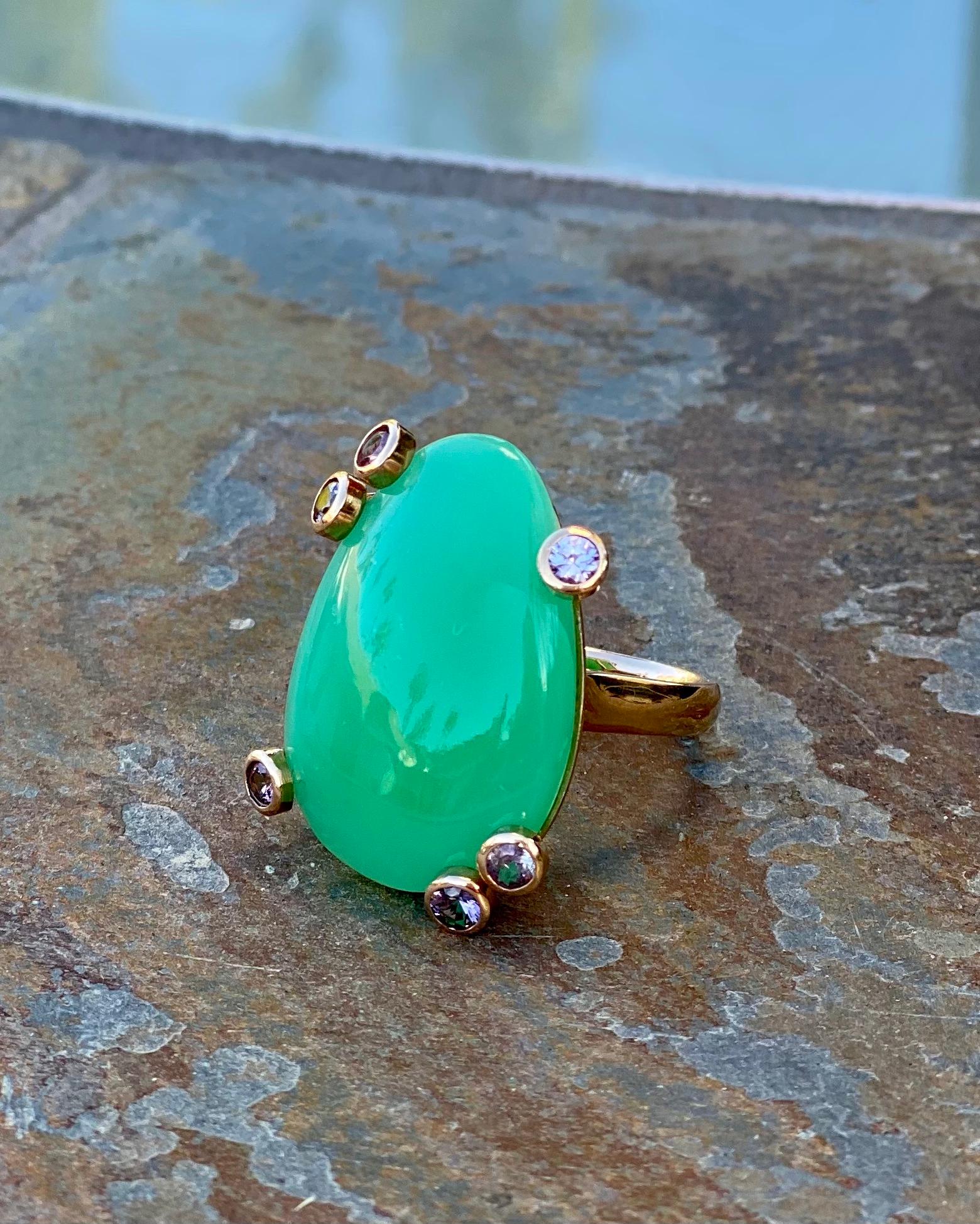 A fancy shape, apple green chrysoprase and spinel cocktail ring, handcrafted in 18 karat yellow gold.

This one-of-a-kind apple green chrysoprase cocktail ring makes a big statement. A beautiful fancy shape, it is accented by purple spinels that