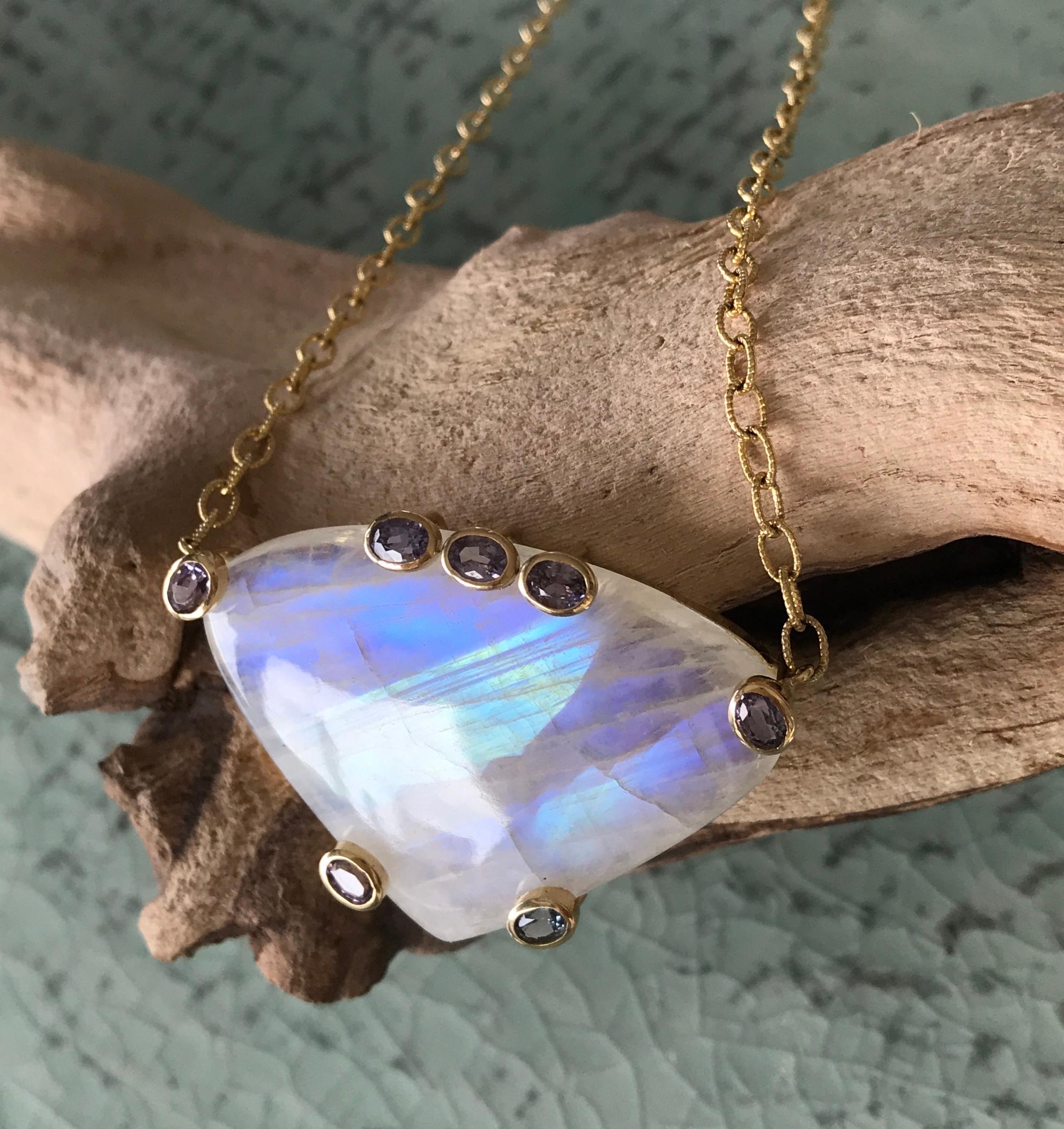 This Joon Han one-of-a-kind rainbow moonstone necklace features a large fancy cut cabochon moonstone as its centerpiece, with oval faceted purple spinel accents. The gorgeous and numerous blue flashes of the rainbow moonstone come to life in the