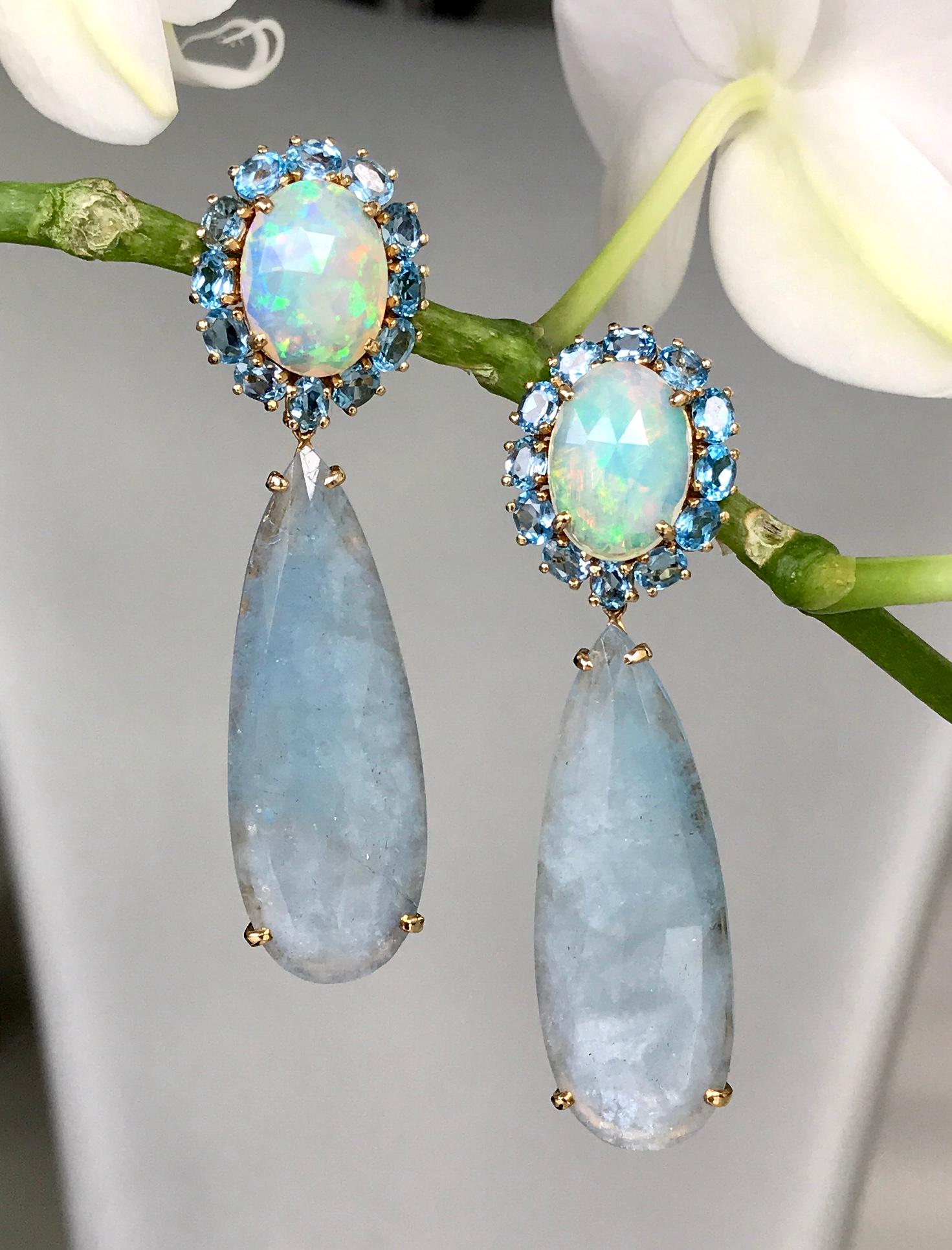 Boucles d'oreilles pendantes en opale, aigue-marine, topaze bleue et diamant, fabriquées à la main en or jaune 18 carats.

Ces exquises opales irisées, entourées de topazes bleues et de gouttes d'aigue-marine taillées en rose, transforment toute