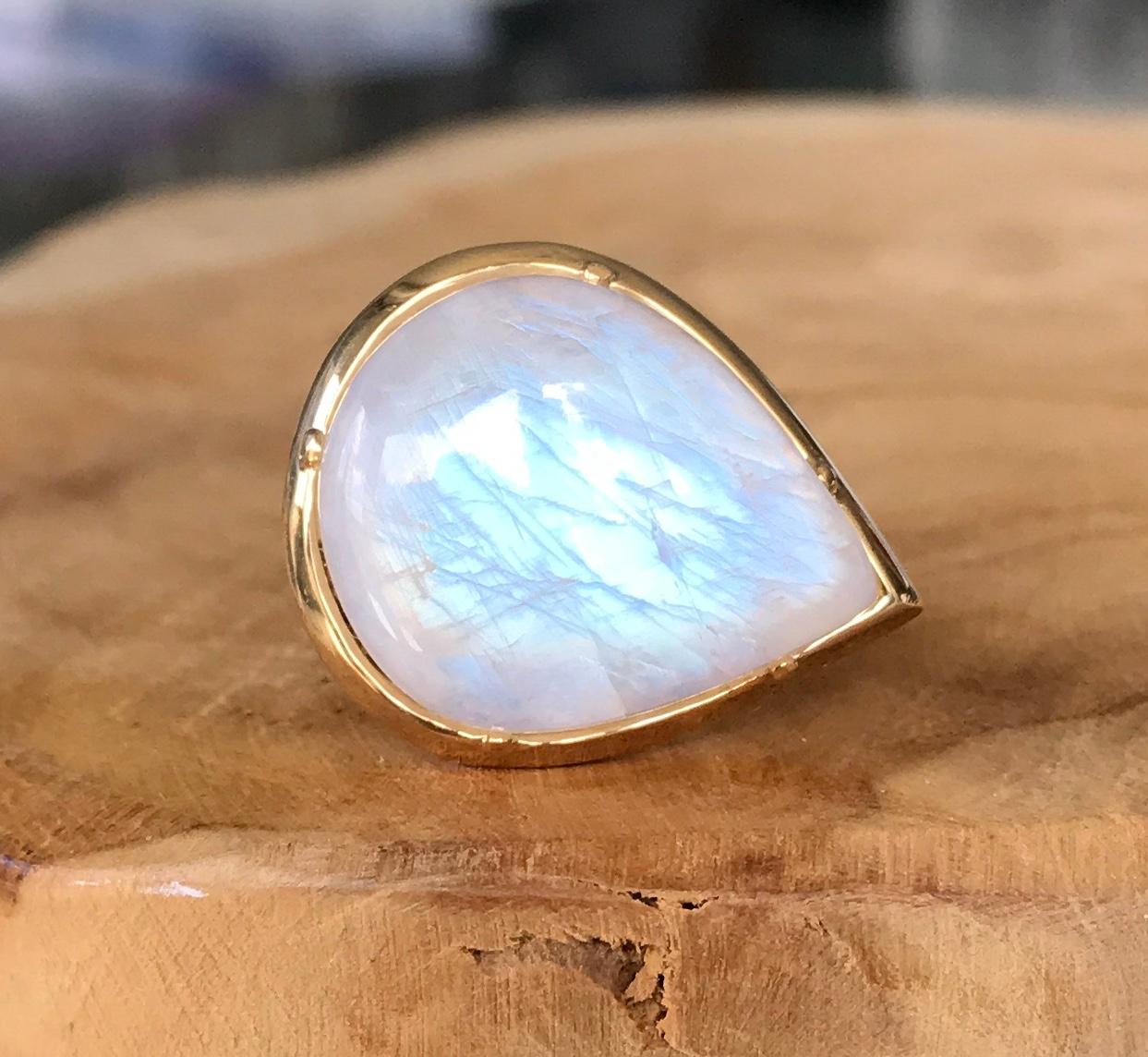 This exquisite Joon Han rainbow moonstone cocktail ring radiates the telltale flashes of blue when reflected in the light. Cut in an elegant fancy cabochon pear shape and handcrafted in 18K yellow gold, it makes a simple but strong statement. Wear