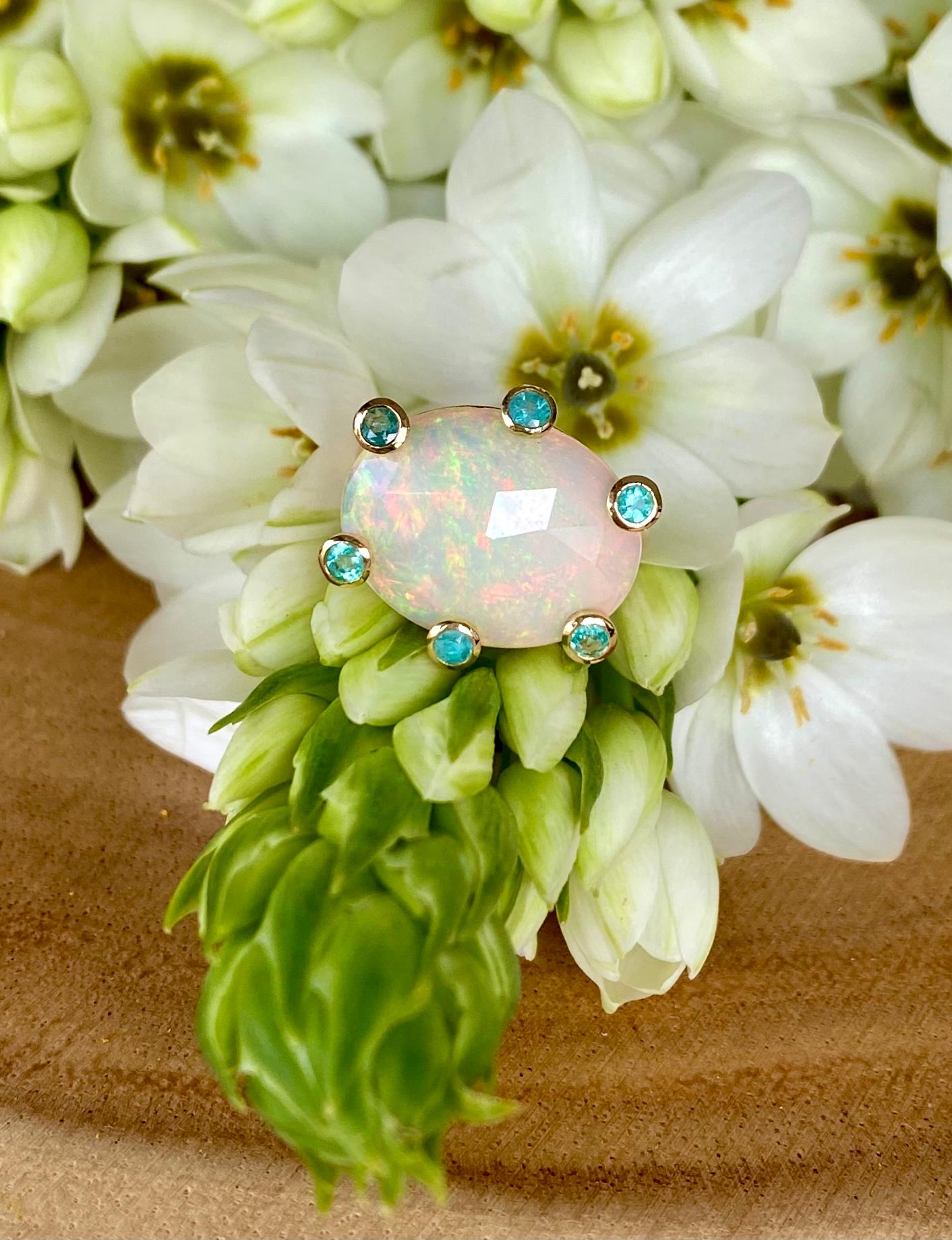 A one-of-a-kind rose cut opal cocktail ring accented with paraiba tourmalines, handcrafted in 18 karat yellow gold.

This beautiful kaleidoscopic opal shimmers with the fire of rainbow colors in different lights. Accented with sparkling paraiba