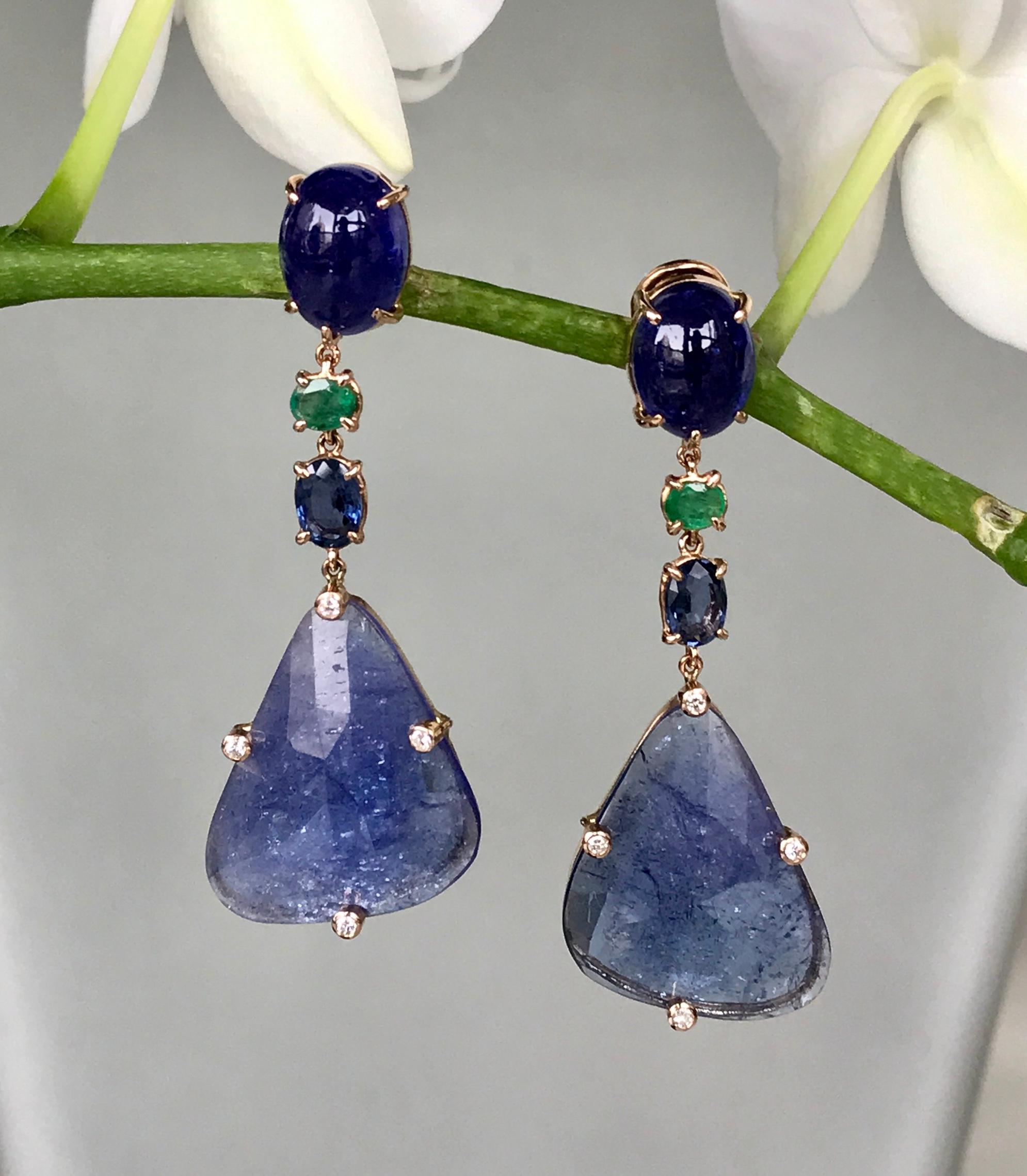 Joon Han one-of-a-kind drop dangle earrings of fancy shaped tanzanite slices are topped with oval cabochon tanzanites, and faceted emeralds and blue sapphires. These luxurious blue and green earrings make an elegant statement, and the vibrant colors