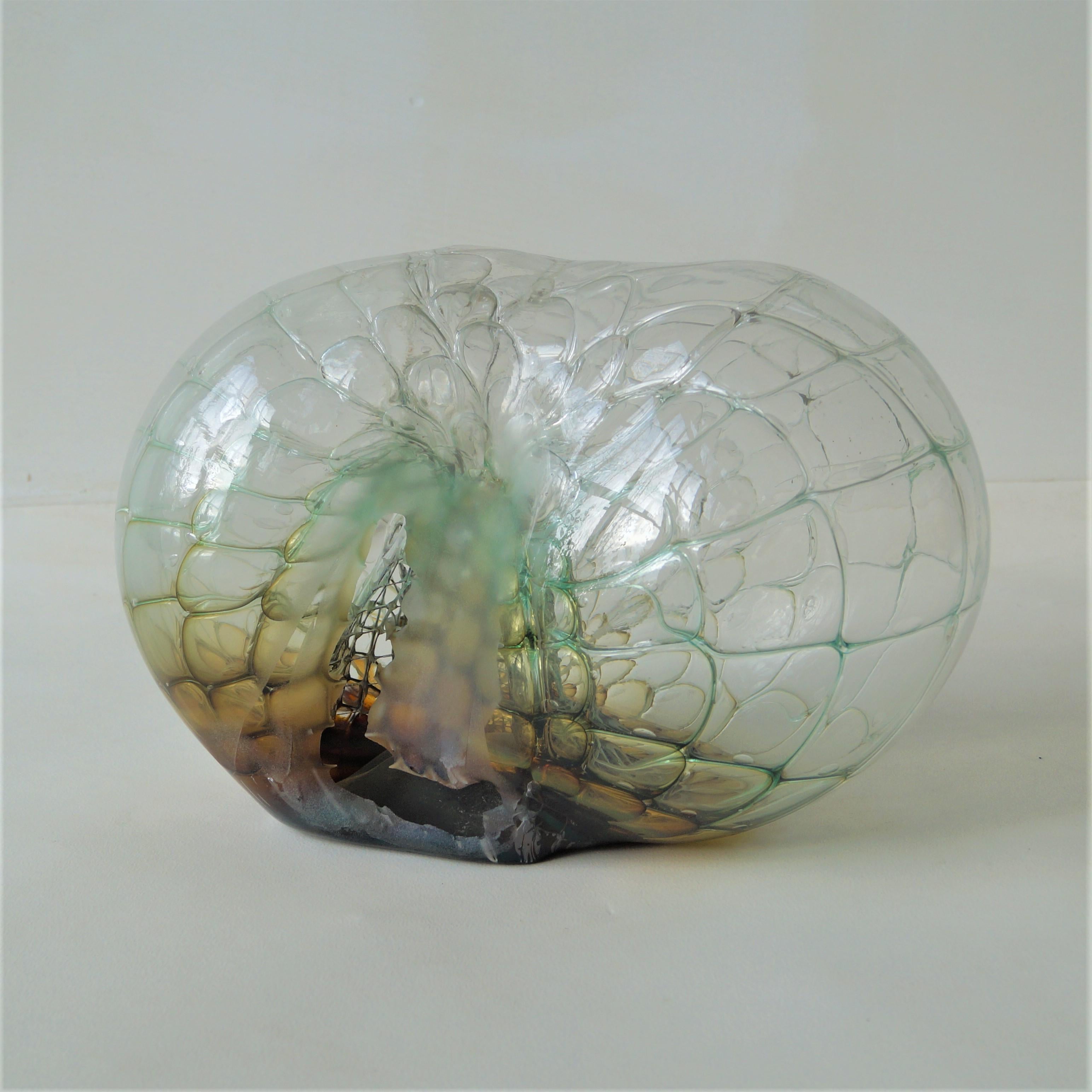 Eine beeindruckend große Skulptur aus klarem Glas mit einem Kern aus grünem/gelbem/kognakfarbenem Glas, einer Überlagerung aus klarem Glas und einem Metallgeflecht (Bienenwaben) im Inneren. Schöpfer ist Jorg F. Zimmerman, geschätzt ca. 2000. 

Das