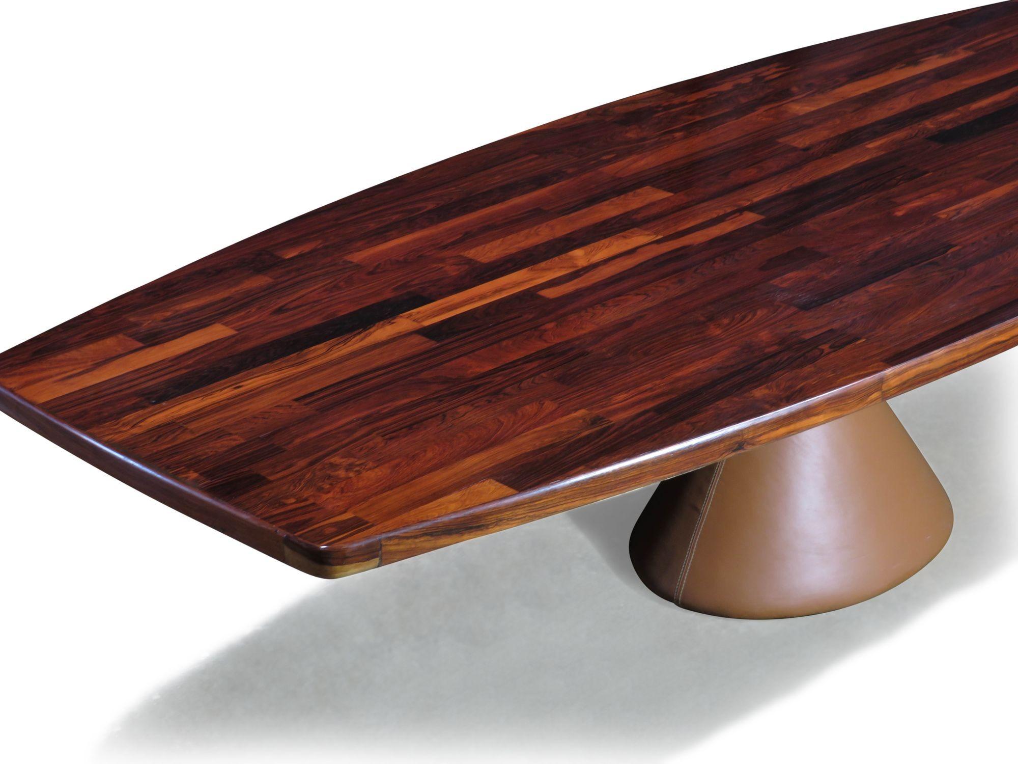 L'emblématique table Guanabara conçue par Jorge Zalszupin pour L'Atelier, 1959. Il est doté d'un impressionnant plateau en bois de rose en forme de bateau sur une base massive en béton recouverte d'un cuir de selle. Le plateau en patchwork présente