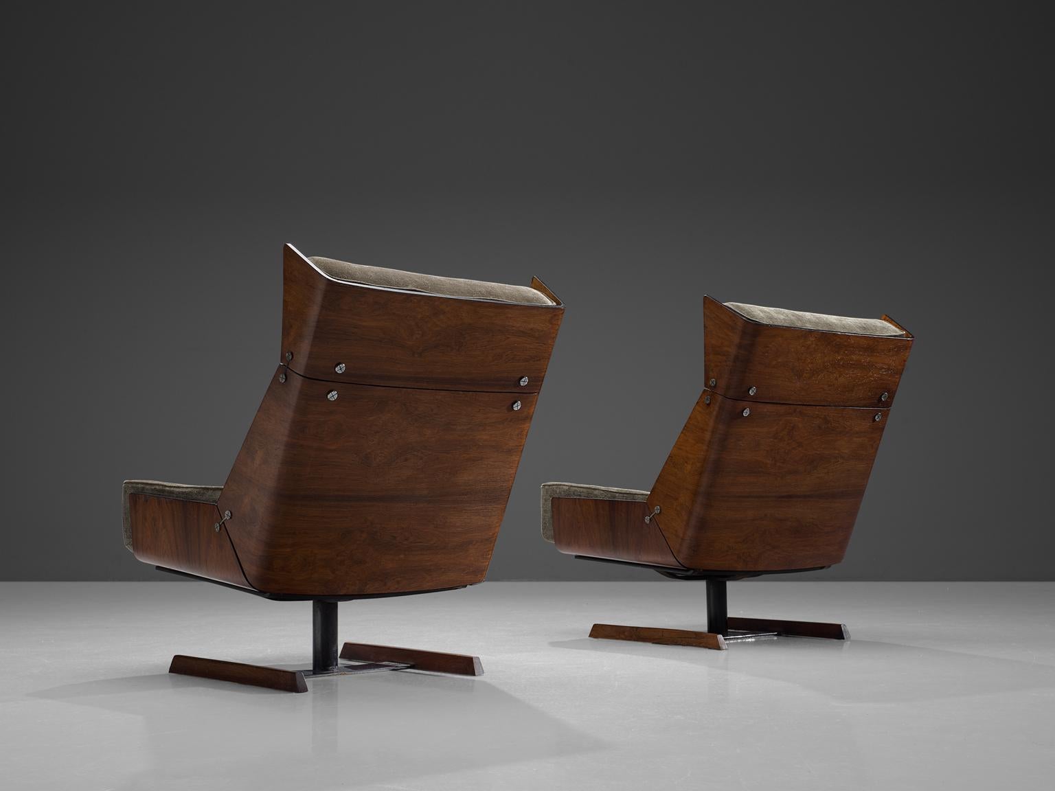 Pair of lounge chairs, in rosewood, metal and velvet, Brazil, 1960s.

Three shells, which consist of bended rosewood plywood, are combined by metal elements that connect the shells with each other. Exceptional are the sled or slipper legs in metal