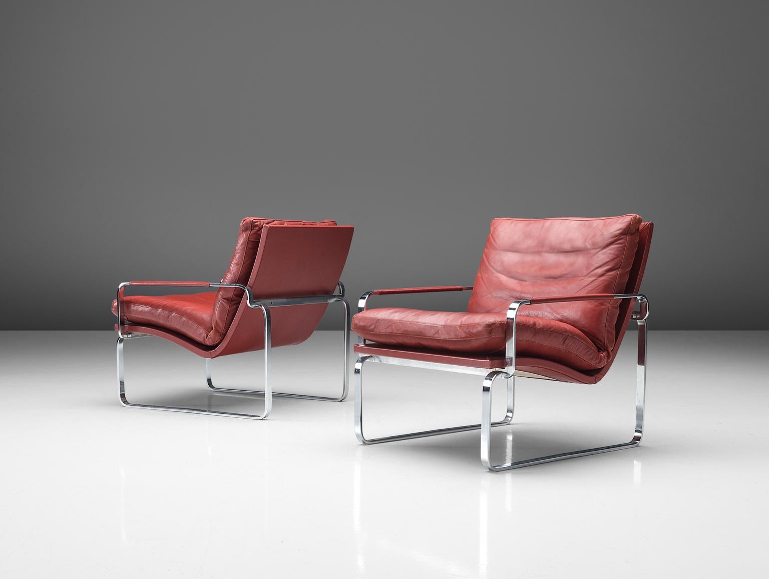 Jørgen Lund for Ole Larsen, BO 911 armchairs, red leather, steel, Denmark, 1980s.

Set of two modern armchairs chairs in steel and leather. Interesting detail is the leather that covers the thin metal armrests and the sculptural shape of the steel