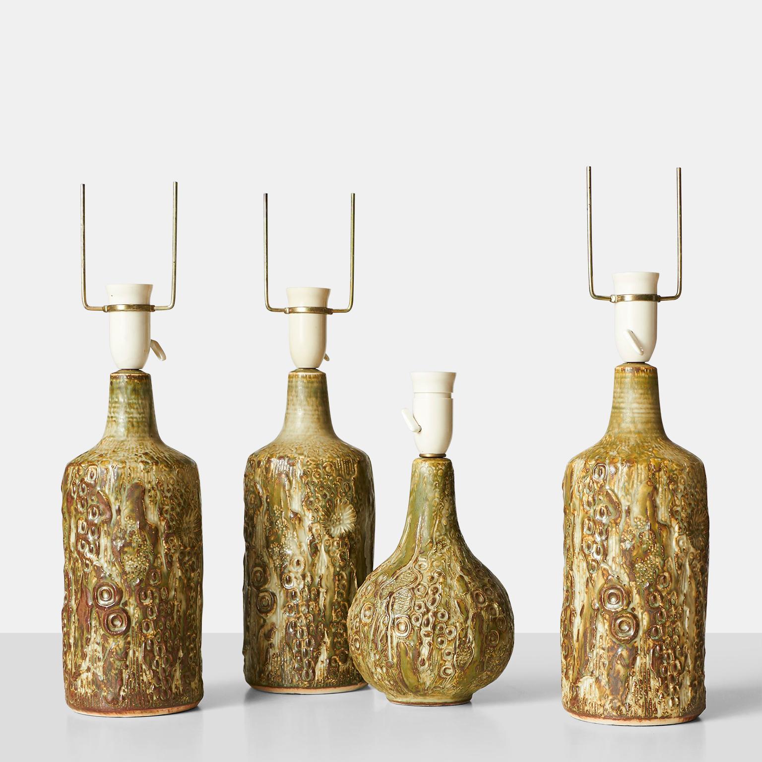 Four stoneware table lamps by Jorgen Mogensen for his own studio. Organic textures to the body of the lamps and earthen colors that were typical of the style. The dimensions listed do not include the harps. The lamps are sold with the harps and