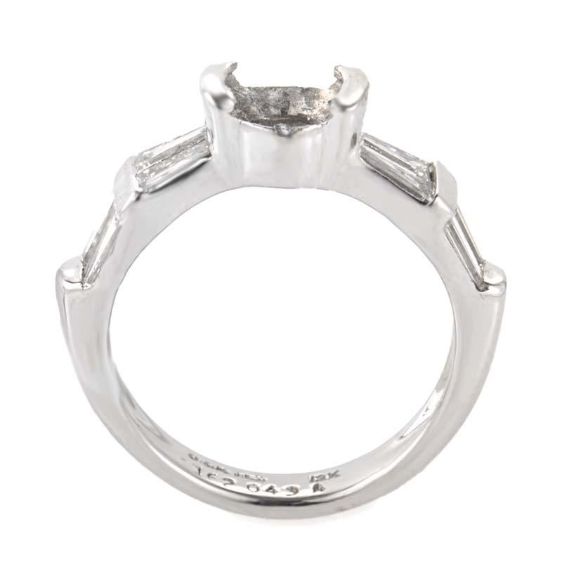 This engagement ring mounting from Jose Hess is simple and sophisticated. It is made of 18K white gold and boasts shanks set with ~1.20ct of tapered diamond baguettes.
