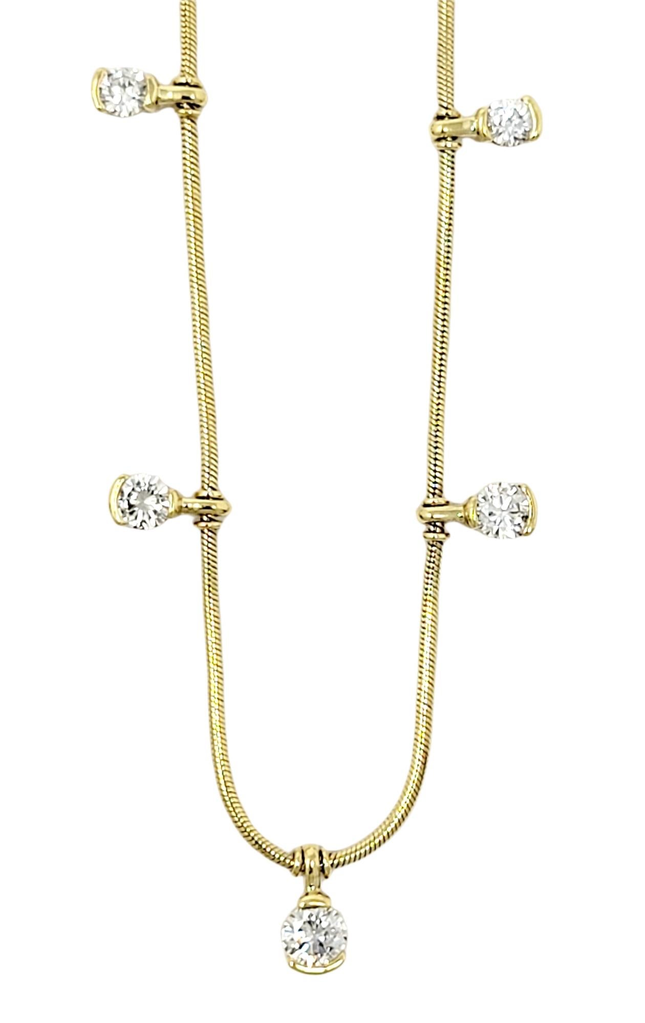 This gorgeous diamond station necklace is the perfect blend of simplicity and elegance.  Featuring a delicate snake chain and a dangling diamond motif, this lovely necklace goes with just about everything. This beautiful piece features 5 half bezel