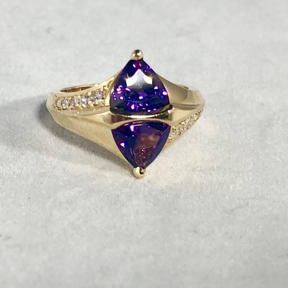 Jose Trillos 18 karat Amethyst and diamond cocktail ring. This piece is created in 18 karat yellow gold weighing 7.1 grams/ 4.6 dwt. The geometric design includes 2 trillion cut Amethyst, each amethyst is 6.5mm in size equaling 2.50 carat total