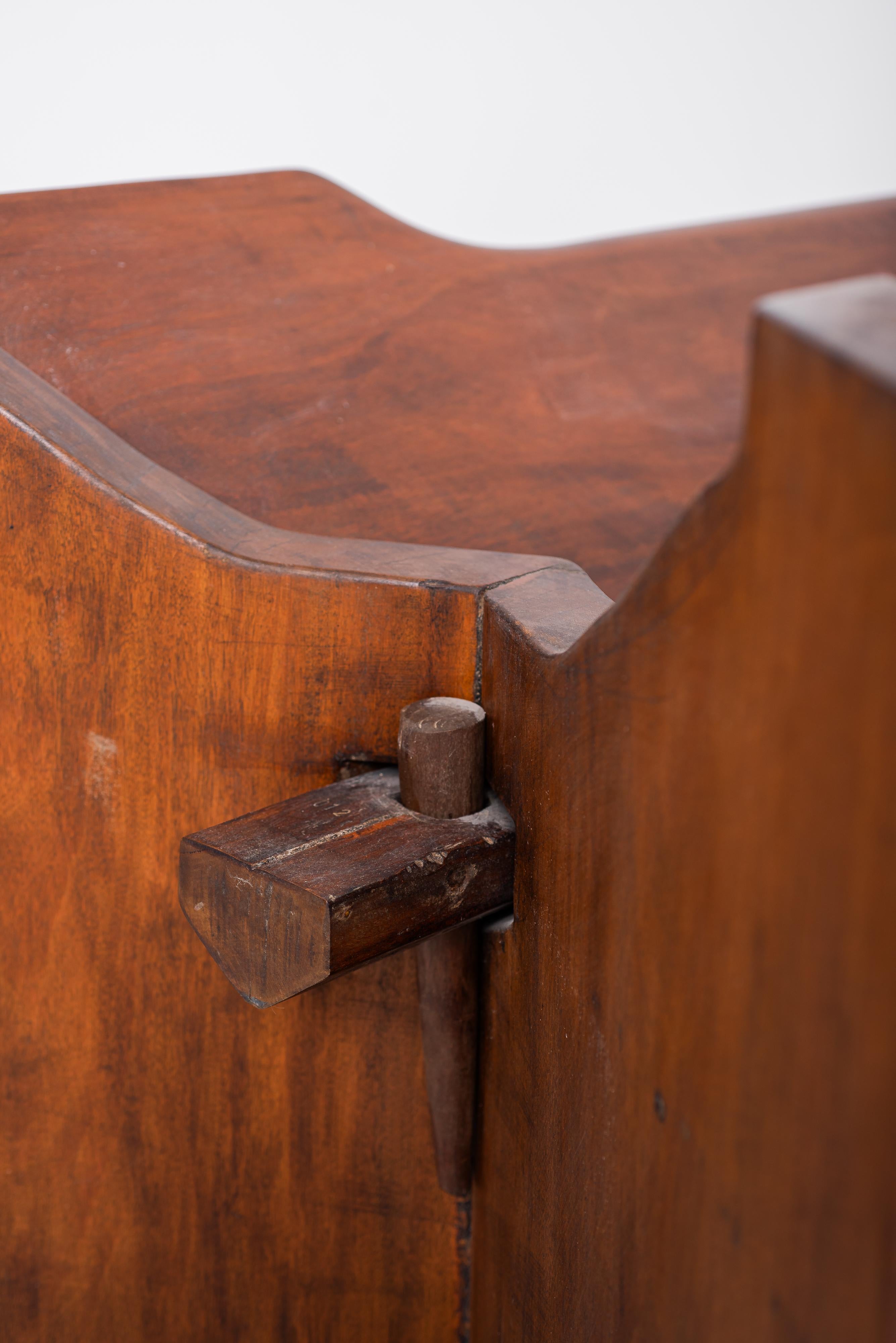 José Zanine Caldas' 1979 dining table is a striking example of his signature style, blending raw natural materials with organic forms. Crafted from wood and tempered glass, the table showcases the beauty of the wood grain and the artist's masterful