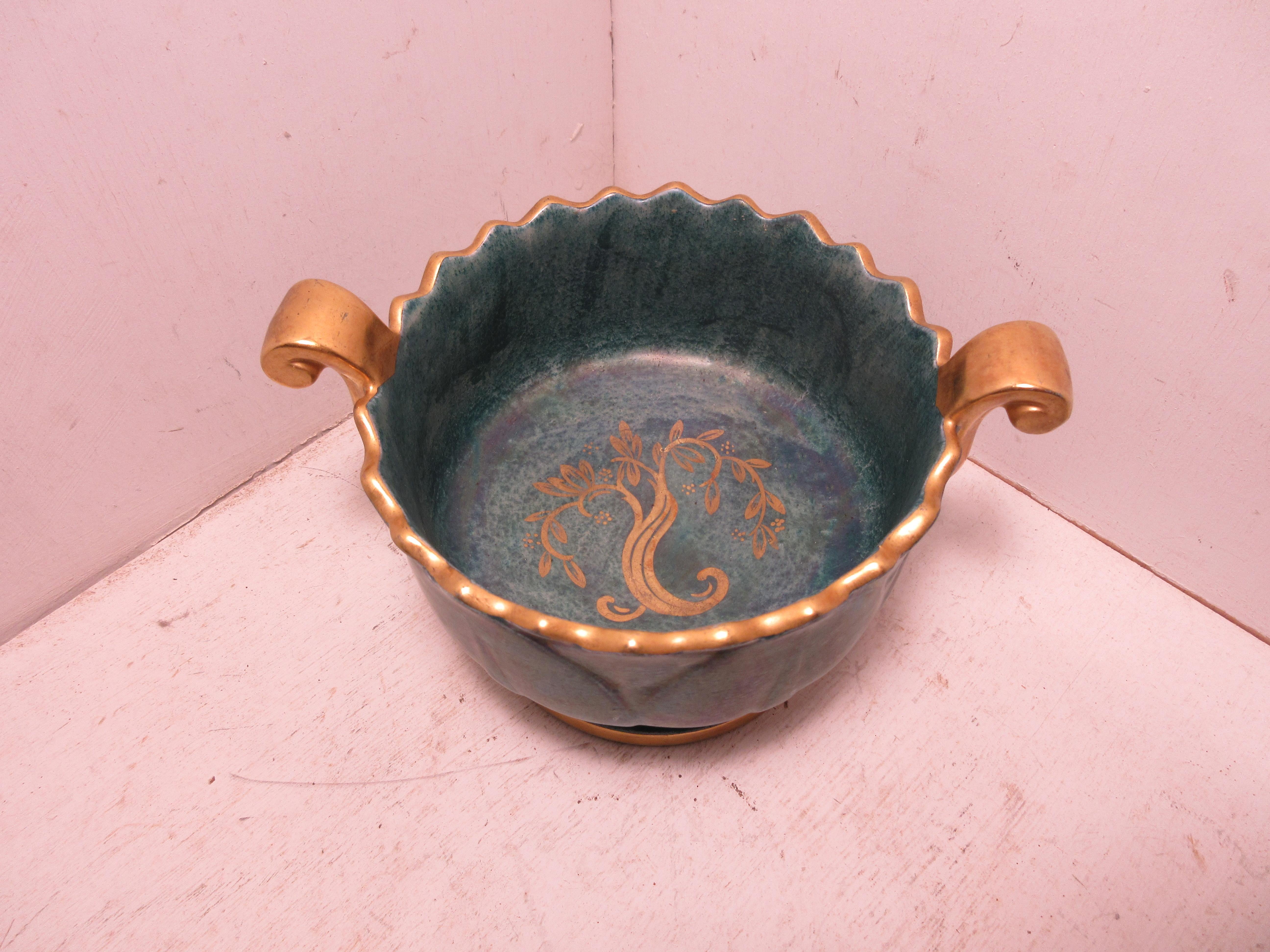 This is a handmade rare Swedish Art Deco ceramic bowl in green and gold luster glaze hand decorated with gold made by the Swedish ceramic artist Josef Ekberg. He was one of Sweden’s top Ceramic artist at the time. He started working at the