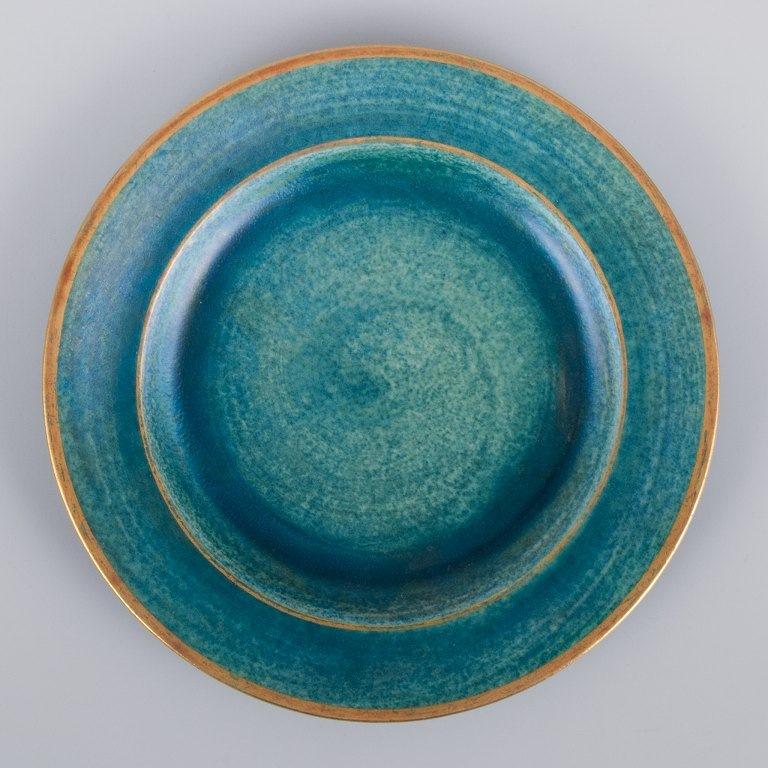 Josef Ekberg for Gustavsberg, Sweden. 
A set of ten ceramic plates with glaze in blue-green tones and a gold rim.
Mid-20th century.
Marked.
In perfect condition.
Dimensions: Diameter 18.5 cm.