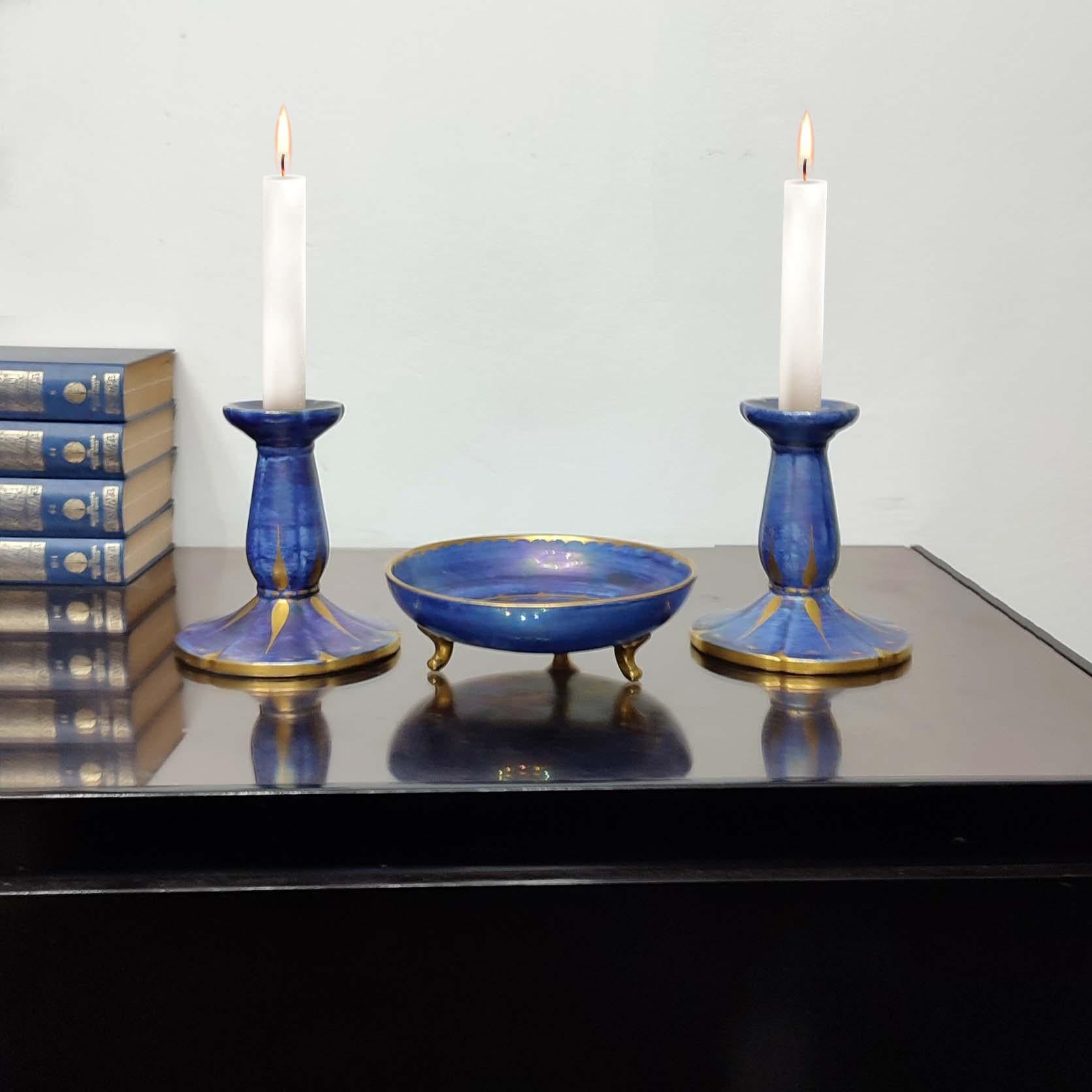 Josef Ekberg for Gustavsberg, Sweden 1931. 
A pair of Art Deco exquisite candlesticks and a three feet vide-poche in glazed ceramics, rare find.
Beautiful blue-purplish glaze and gold decoration, 1931. Manufacturer stamp and artist signature to