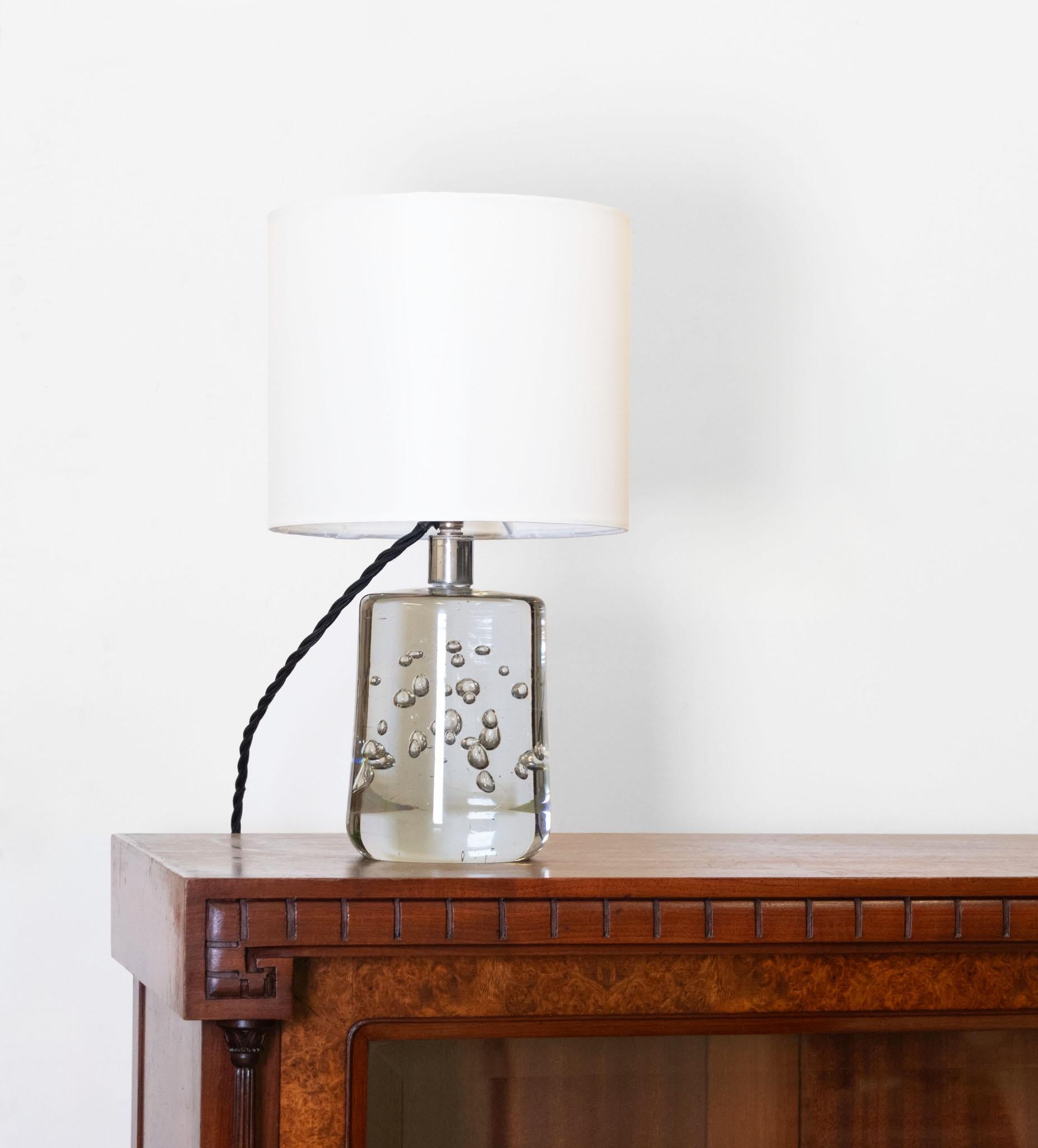 Cylindrical form blown glass table lamp having encased bubbles with a nickel plated stem, designed by Josef Frank (1885-1967) and produced by Svenskt Tenn, Sweden. Circa 1940.

The original bayonet is present and the lamp has been re-wired with 3