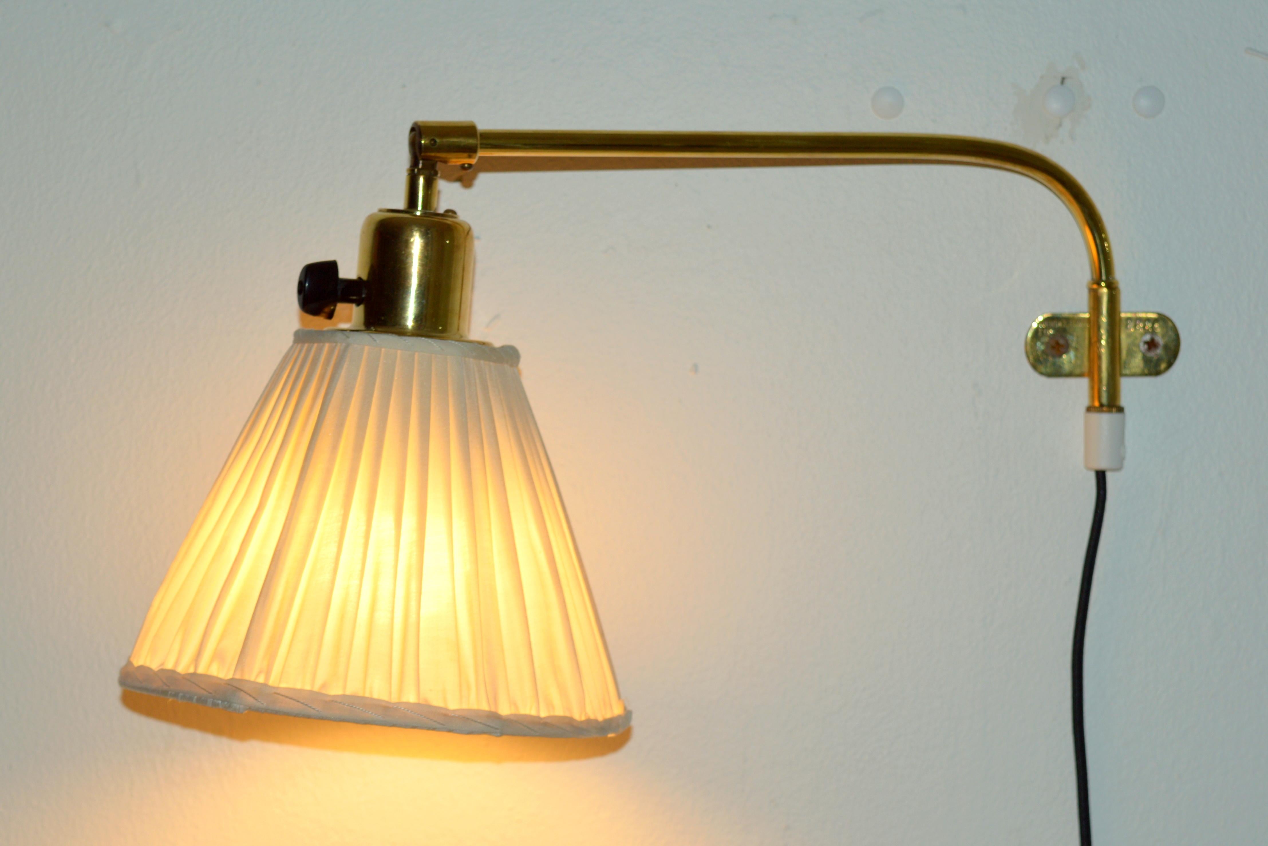 An adjustable brass wall light with a satin fabric shade designed  by Josef Frank. Produced by Svenskt Tenn, Sweden during the 1950s. Configured for plug-in with cord feeding from bottom of stem. Overall Dimensions (inches): 20” H x 7” W x 9” D,