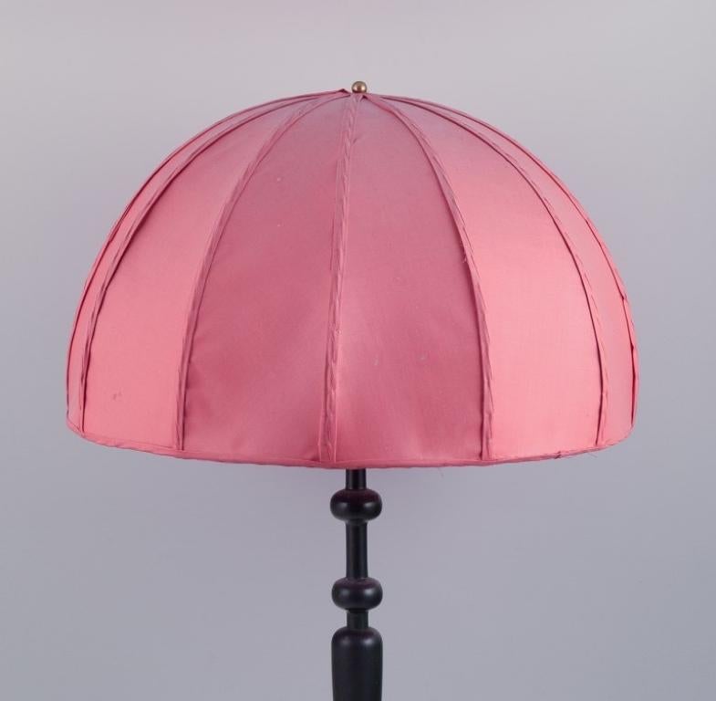 Josef Frank (1885-1967) for Svenskt Tenn, Sweden. 
Large table lamp with a dark pink fabric shade and a black wooden base.
Approximately from the 1960s.
In excellent condition with minor signs of use.
Dimensions: H 78.0 cm x W 50.0 cm (shade).
