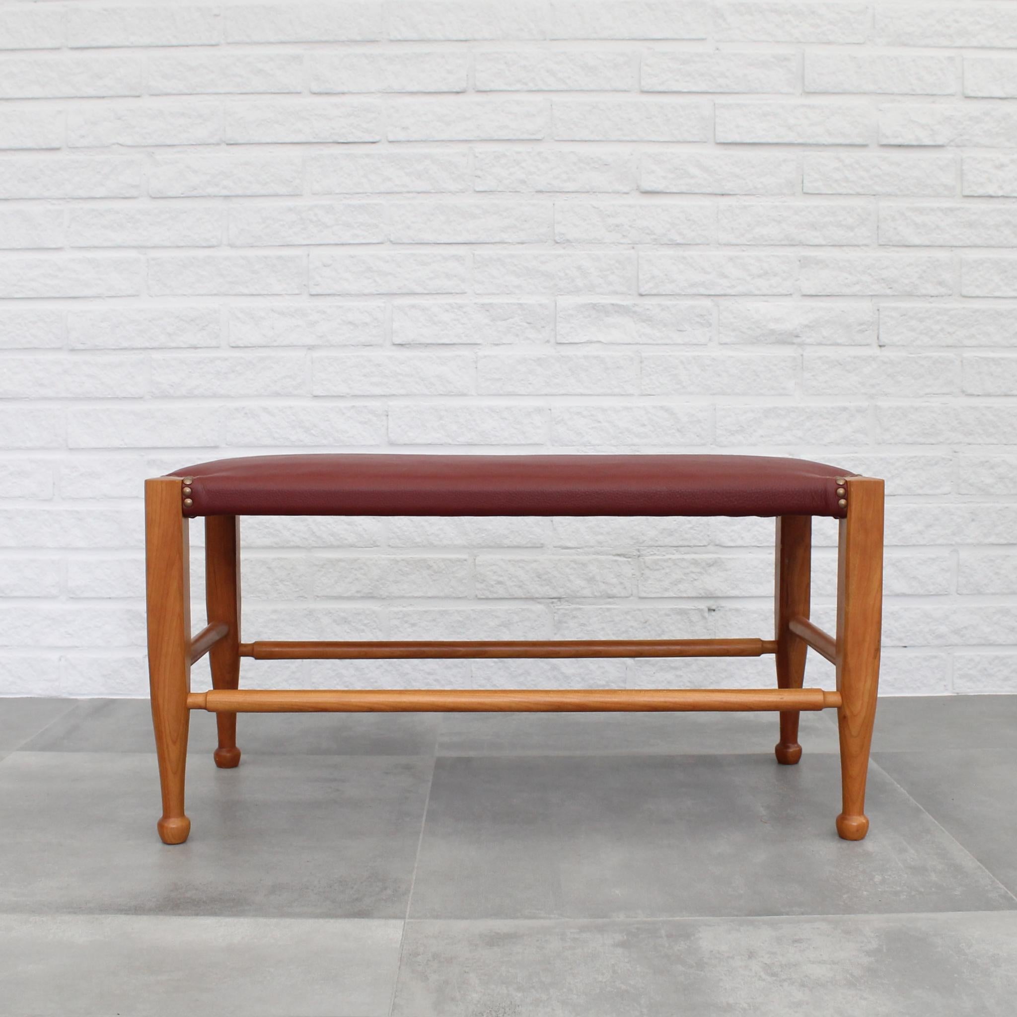Stool model 2009, designed by Josef Frank for Firma Svenskt Tenn. Crafted from solid walnut with vibrant red leather upholstery, it features ornamental brass rivets adorning its legs. Reupholstered in Tärnsjö leather. The Austrian architect Josef