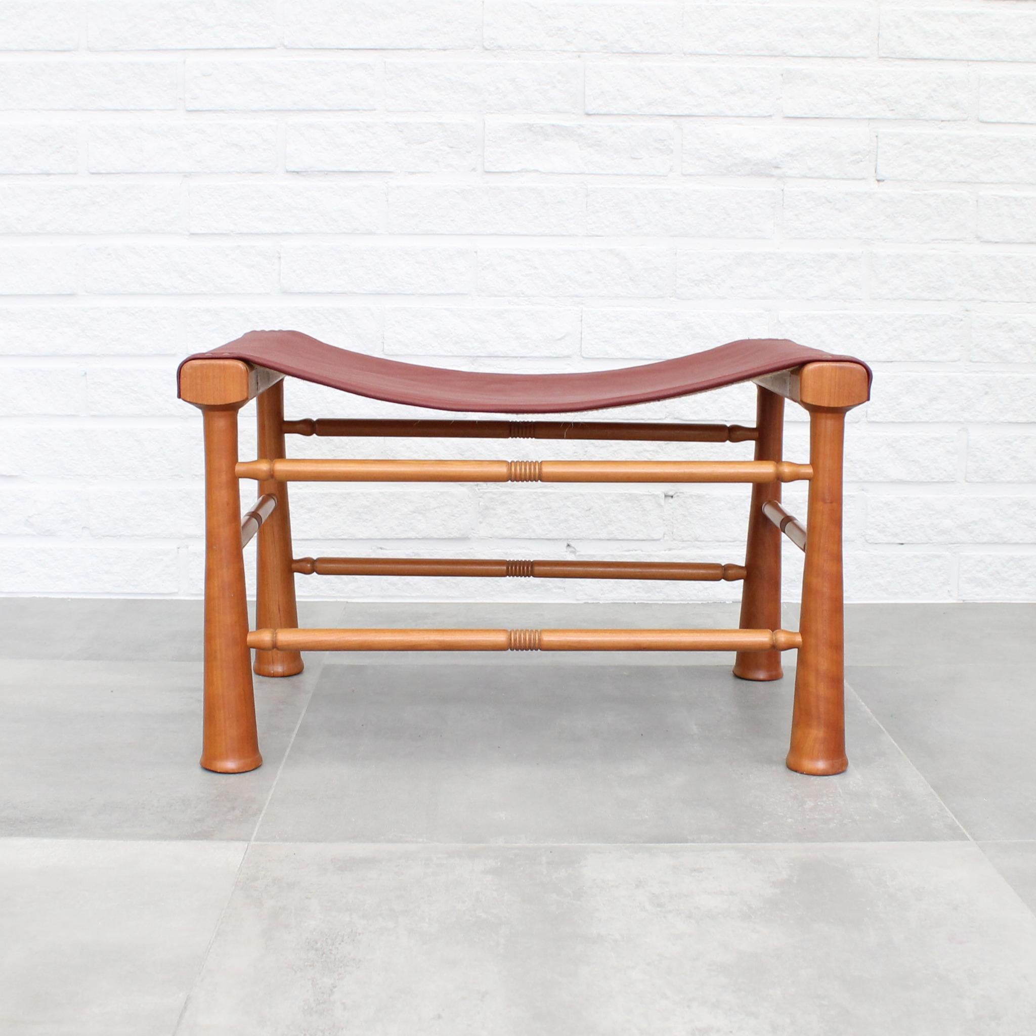 Stool model 972, a 1940 design by Josef Frank for Firma Svenskt Tenn. Crafted from solid mahogany, it features rich red leather upholstery and decorative brass rivets along the sides. This particular model made its debut in a 1940 exhibition with an