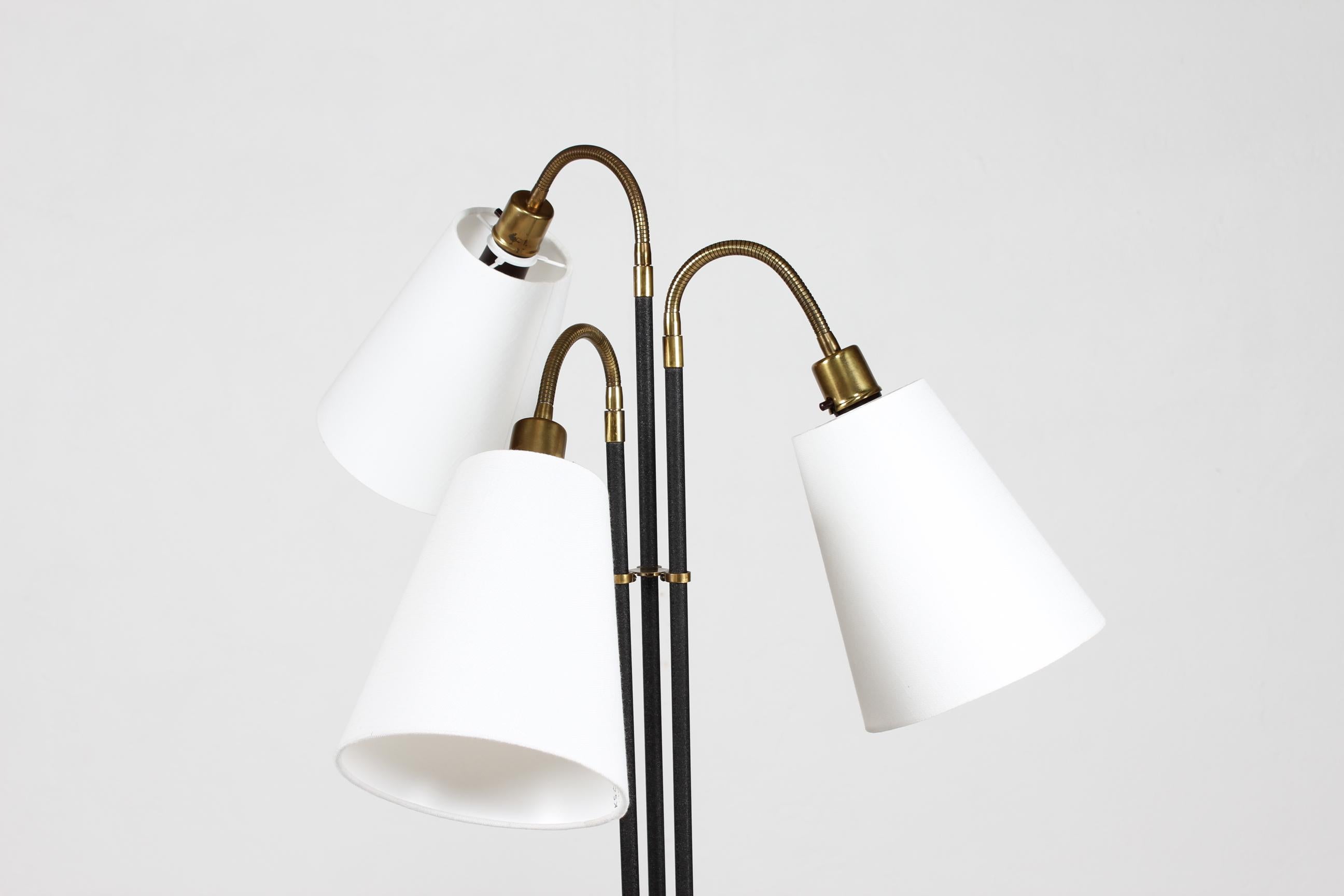 Josef Frank style three-armed floor lamp made of brass and metal with black lacquer with a little structure.
The three arms are individually adjustable and flexible, mounted with new shades.

This floor lamp is made by a Danish lamp manufacturer in