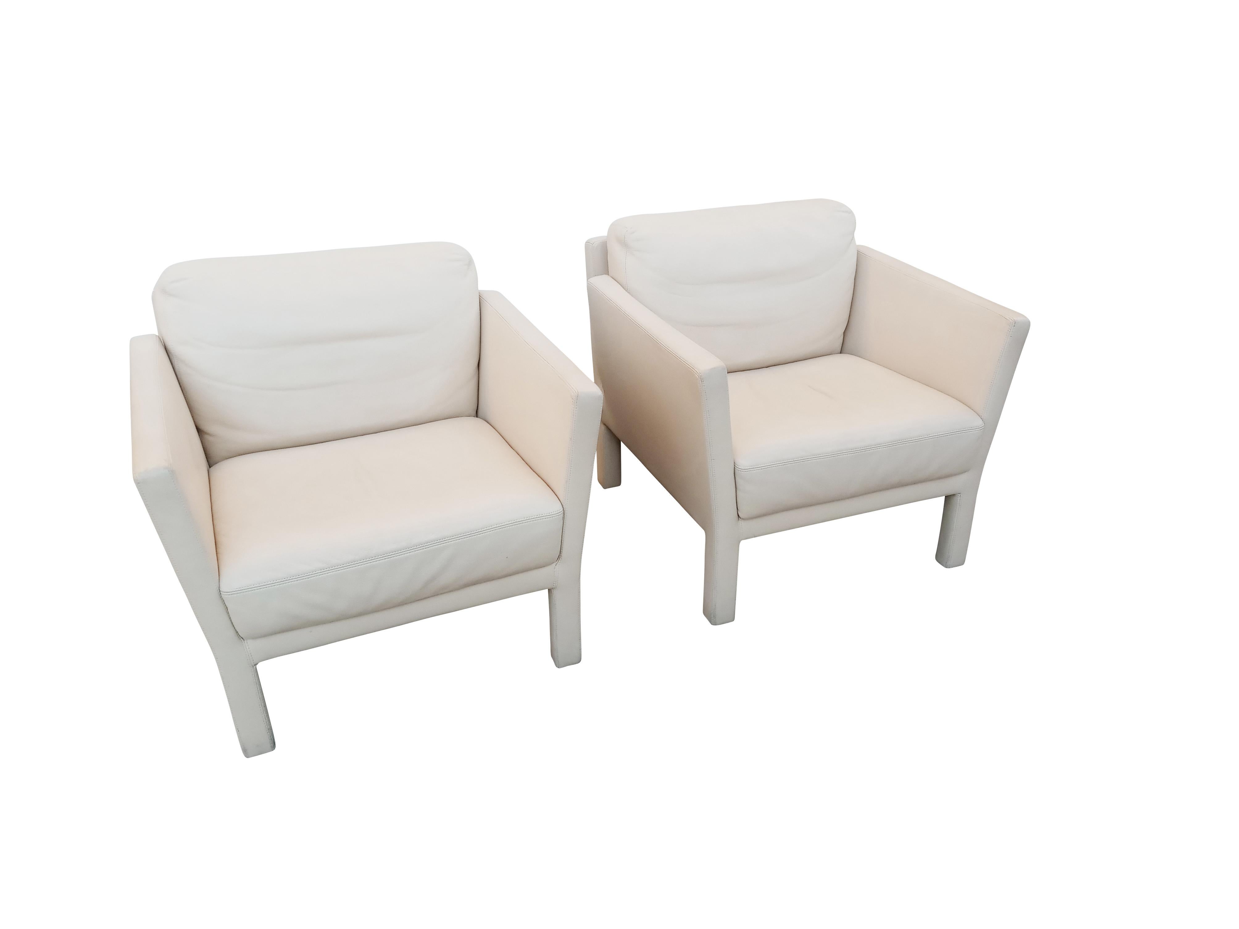 These signed Whittmann chairs are completely clad in ivory white leather. They also have arms that lean and a deliberately designed notch between the back of the arm and the angled backrest. These subtle design cues are likely by the famous