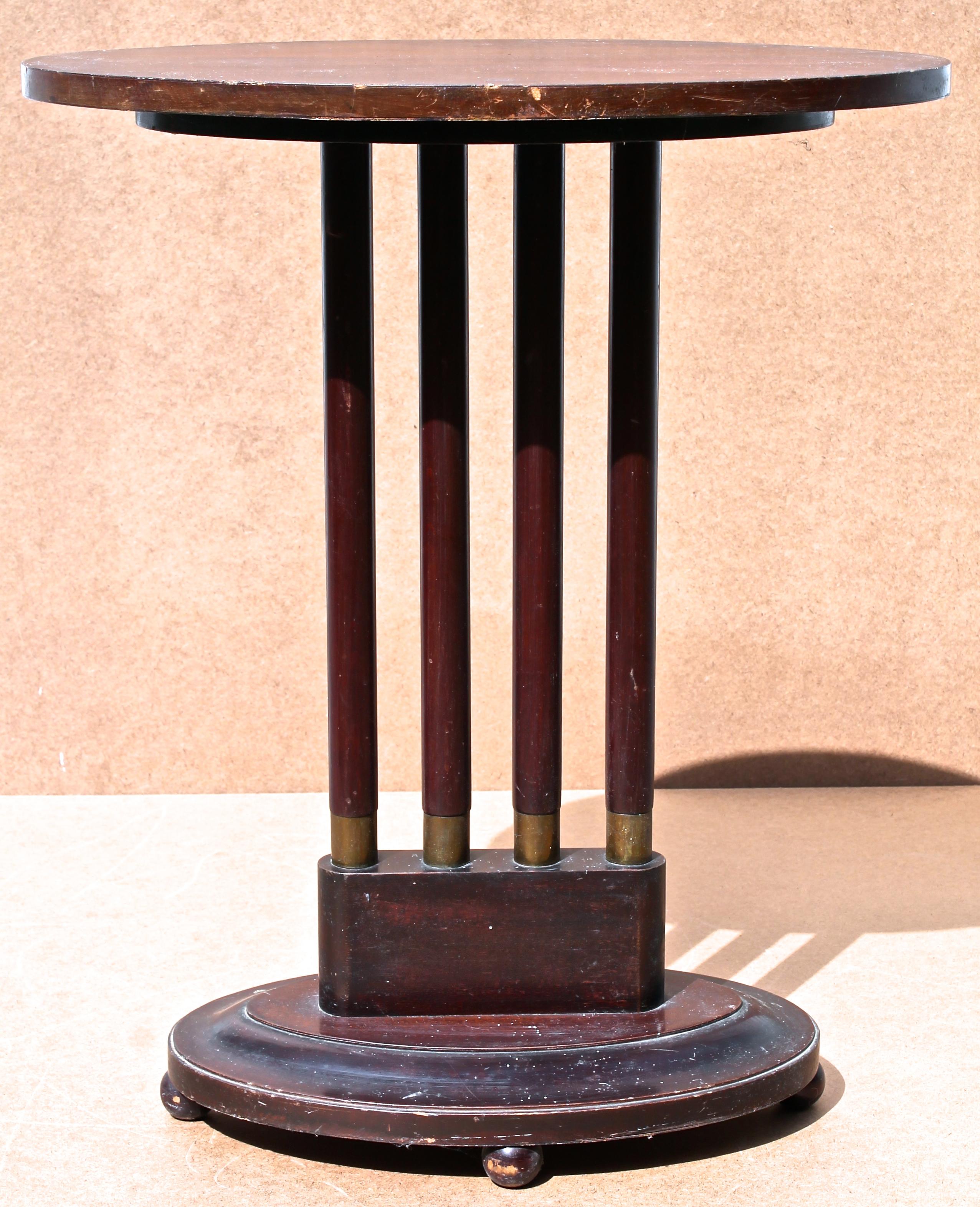 A small elongated oval table, supported by four cylindrical legs with brass end bottoms, that rise from an oval base sitting on four small balls. With an original dark brown surface. Unmarked.