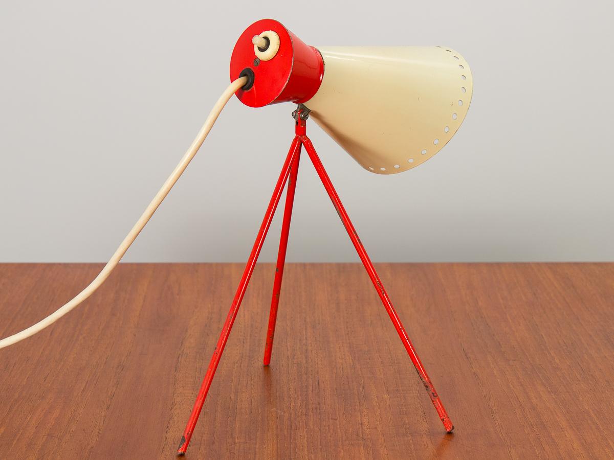 Lampe de table tripode moderniste en rouge et crème contrastés, conçue par le plus célèbre designer industriel tchèque Josef Hurka pour Napako. La base tripode rouge émaillée soutient sans effort l'abat-jour conique en métal. La lampe est en bon