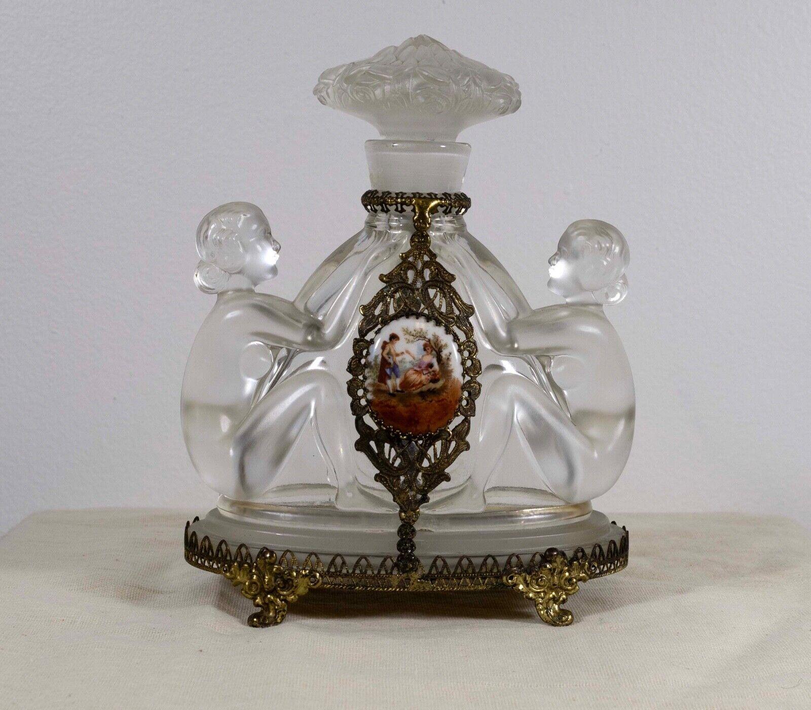 Deliziosa bottiglia di profumo in vetro Art Déco disegnata da Joseph Inwald, Cecoslovacchia, anni '30. Nudi figurativi in vetro trasparente, tappo a dauber floreale, metallo dorato e placca in porcellana. Un elegante oggetto da collezione vintage.
