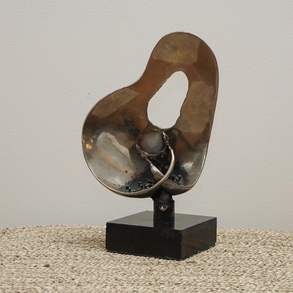 The table sculpture shown here is by Canadian artist Josef Patriska. Featuring a black marble base, the organic modernist sculpture is made from cast polished nickel. In the center is a mounted piece of agate.