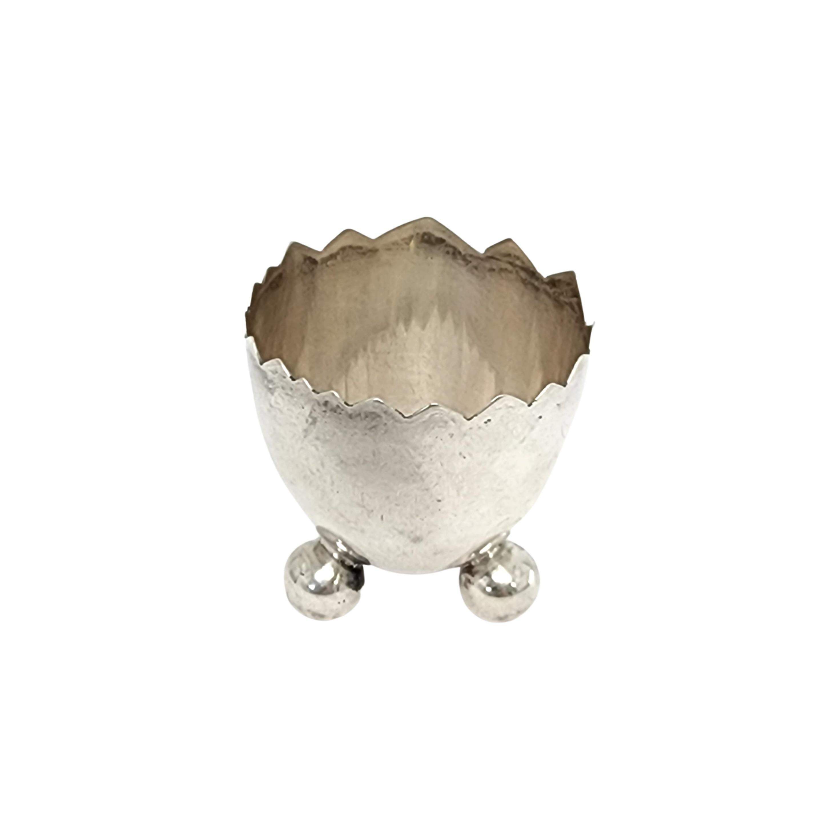 800 silver egg cup by Josef Pauser of Germany.

No monogram

An egg cup in the shape of a cracked egg featuring 3 ball feet.

Measures approx 1 1/2