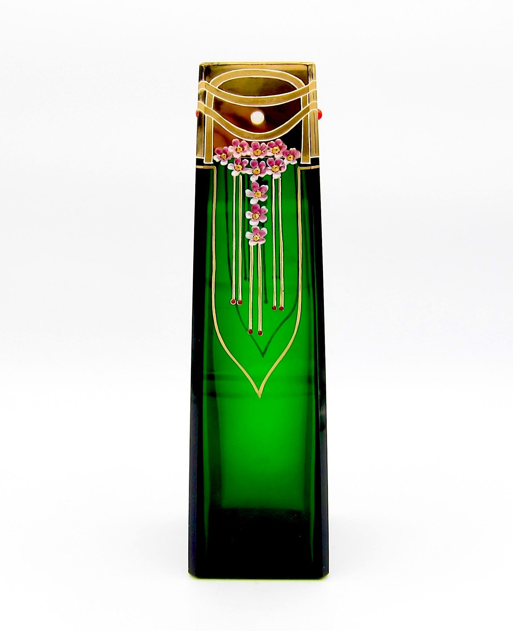 A rectangular antique art glass vase with beveled edges from the Josef Riedel Glassworks at Polaun, dating circa 1900-1910. The dark green glass vessel was mould-blown and decorated in polished gold work ornament with raised, ivory-colored enamel