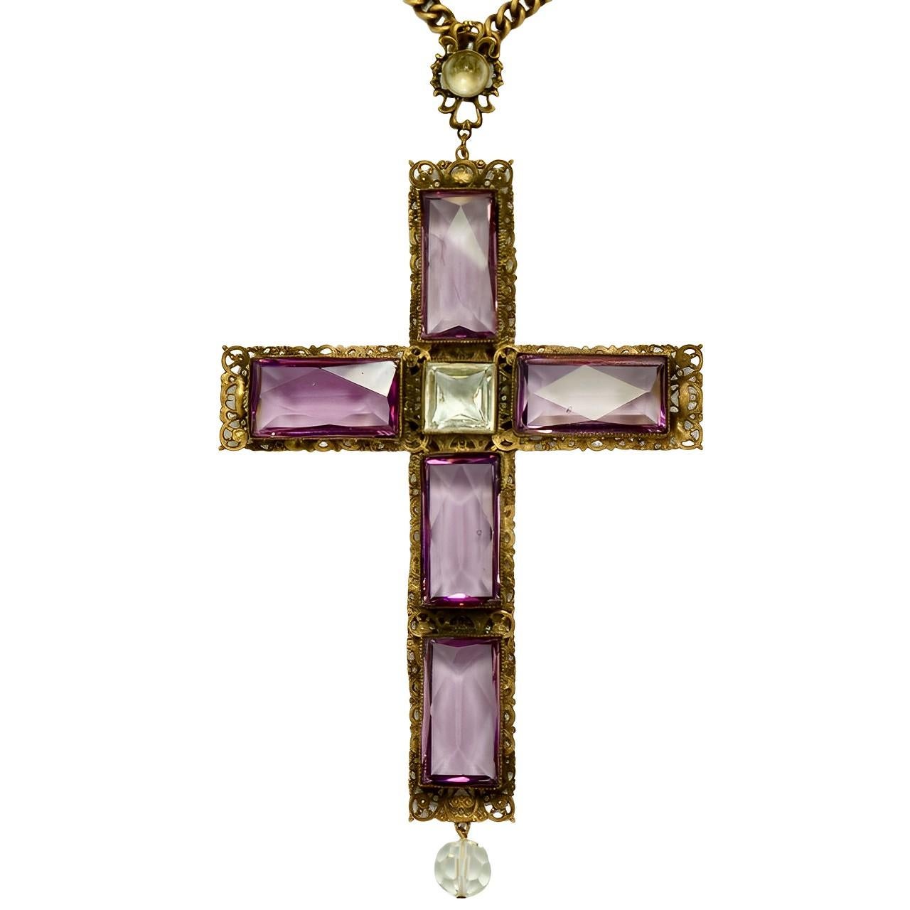 Splendido ciondolo e collana con croce grande di Joseff of Hollywood, con finitura antica placcata in oro russo. La croce è fissata alla catena con una maglia ornata da un cristallo cabochon trasparente. La collana ha una chiusura ad anello che è