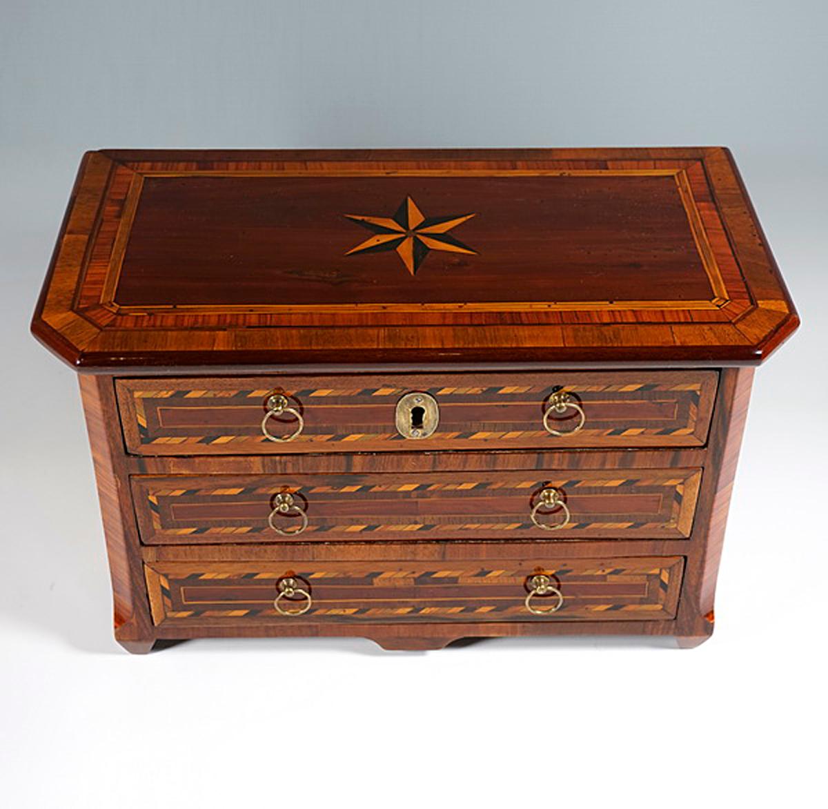Miniature furniture made by hand in high quality: spruce body, veneered with walnut and numerous precious woods, marquetry in the form of fields and bands, star inlay on the top, smooth surfaces, bevelled side edges on the front, small butt feet