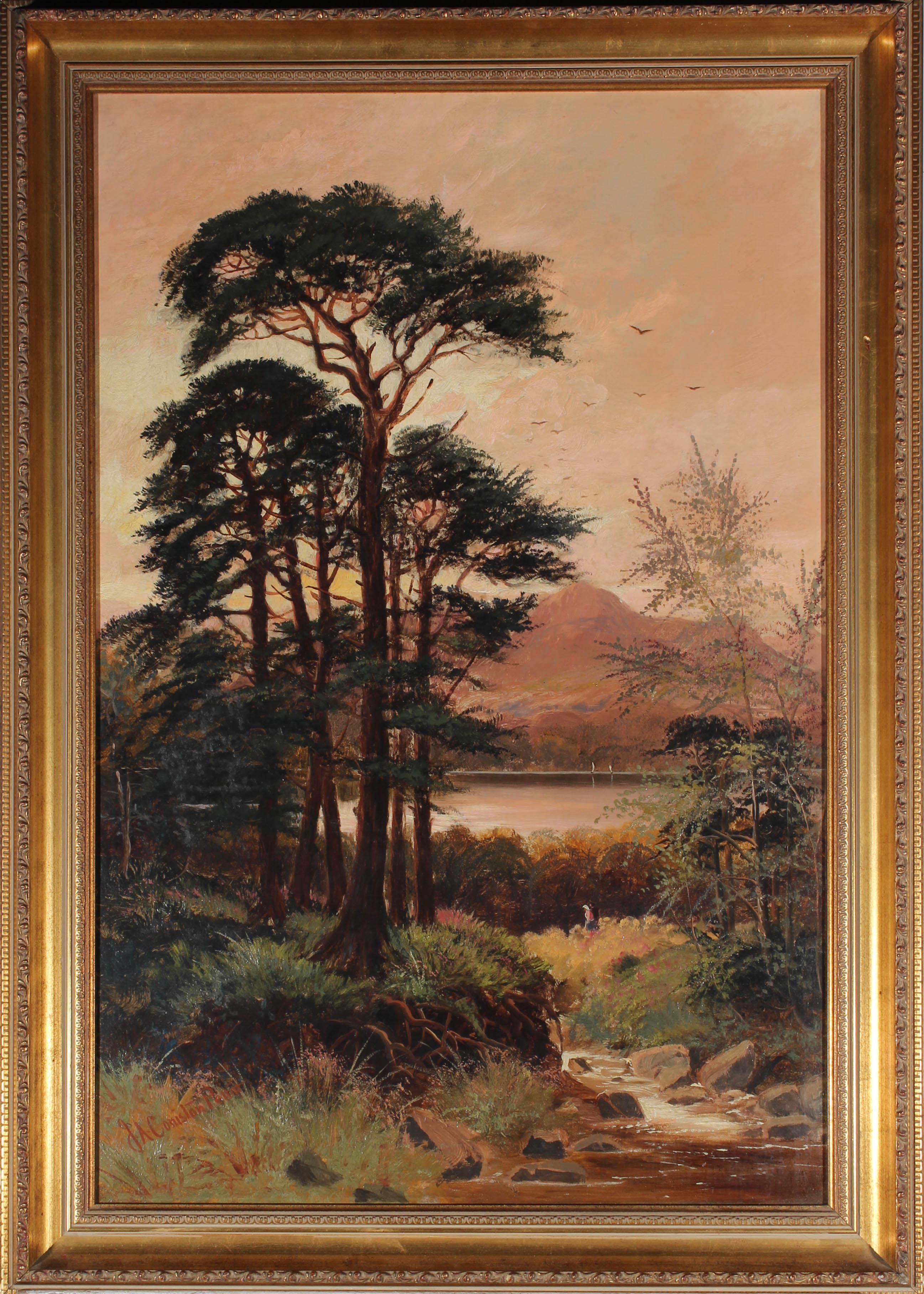 A picturesque early 20th Century landscape in oil showing a wood on the shore of Coniston Lake, in the Lake District, with a distant mountain on the horizon. Two figures take an evening stroll through the undergrowth and large Scots pine trees add