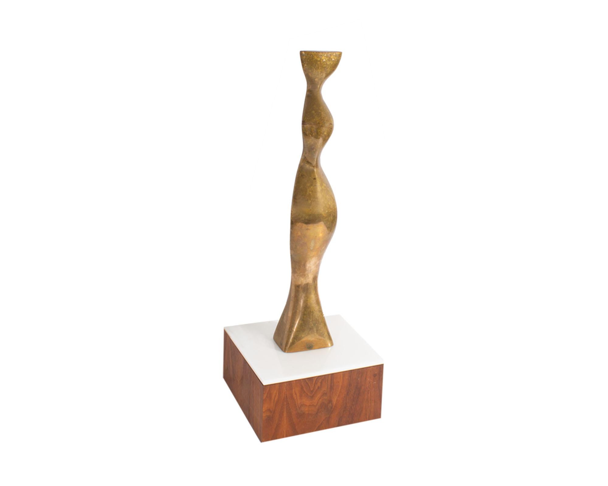 A 1980 limited edition bronze sculpture by American artist Joseph Burlini (born 1937). This sculpture is composed of a metal abstract and curved female figure attached to a white acrylic and wood base. The piece is signed “Joseph A. Burlini” on side