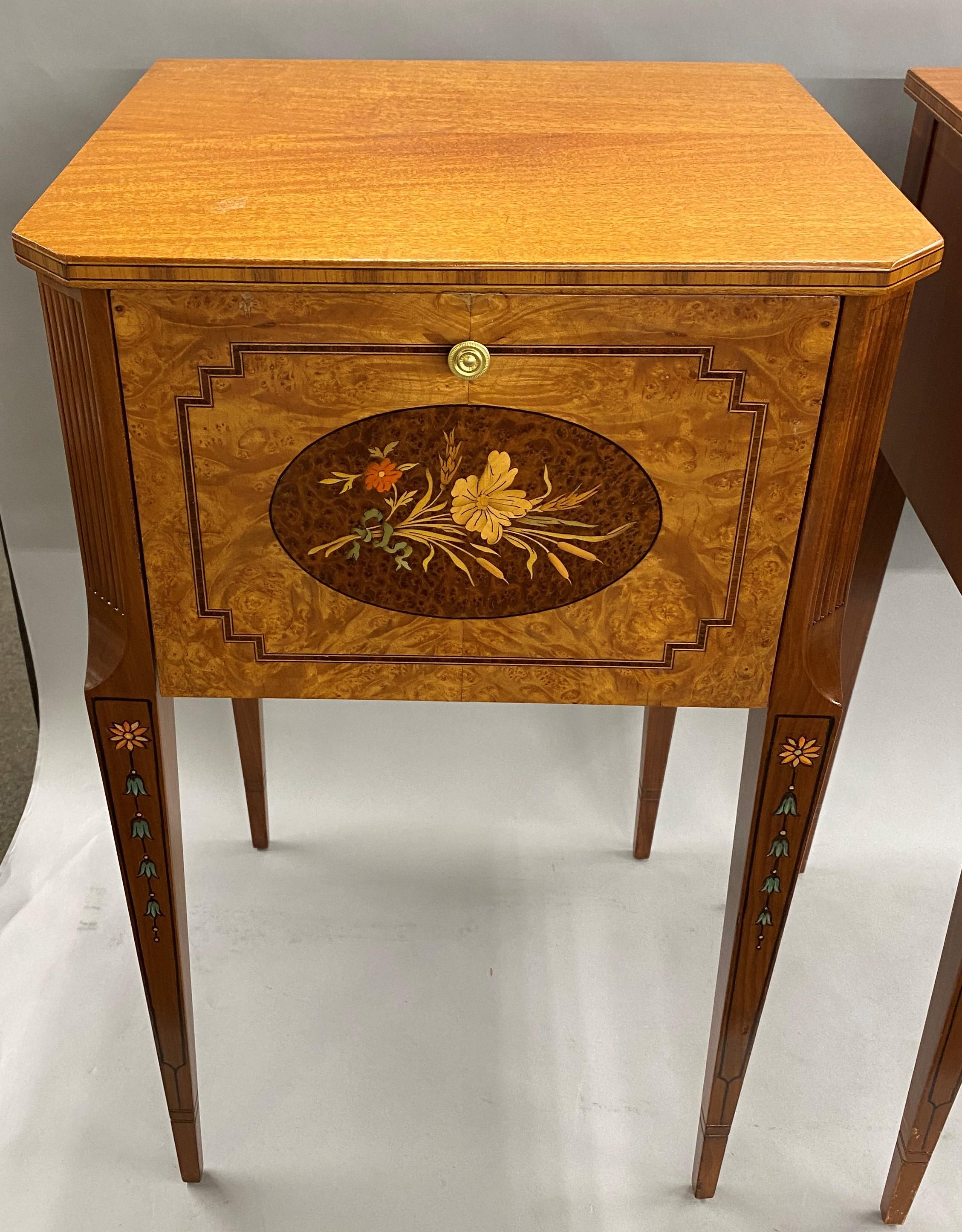 An eye catching pair of mahogany nightstands or end tables by Joseph Gerte, Boston, MA, with beautifully inlaid foliate panels featuring various woods on the hinged drop fronts, and canted reeded corners, supported by tapered paint decorated square
